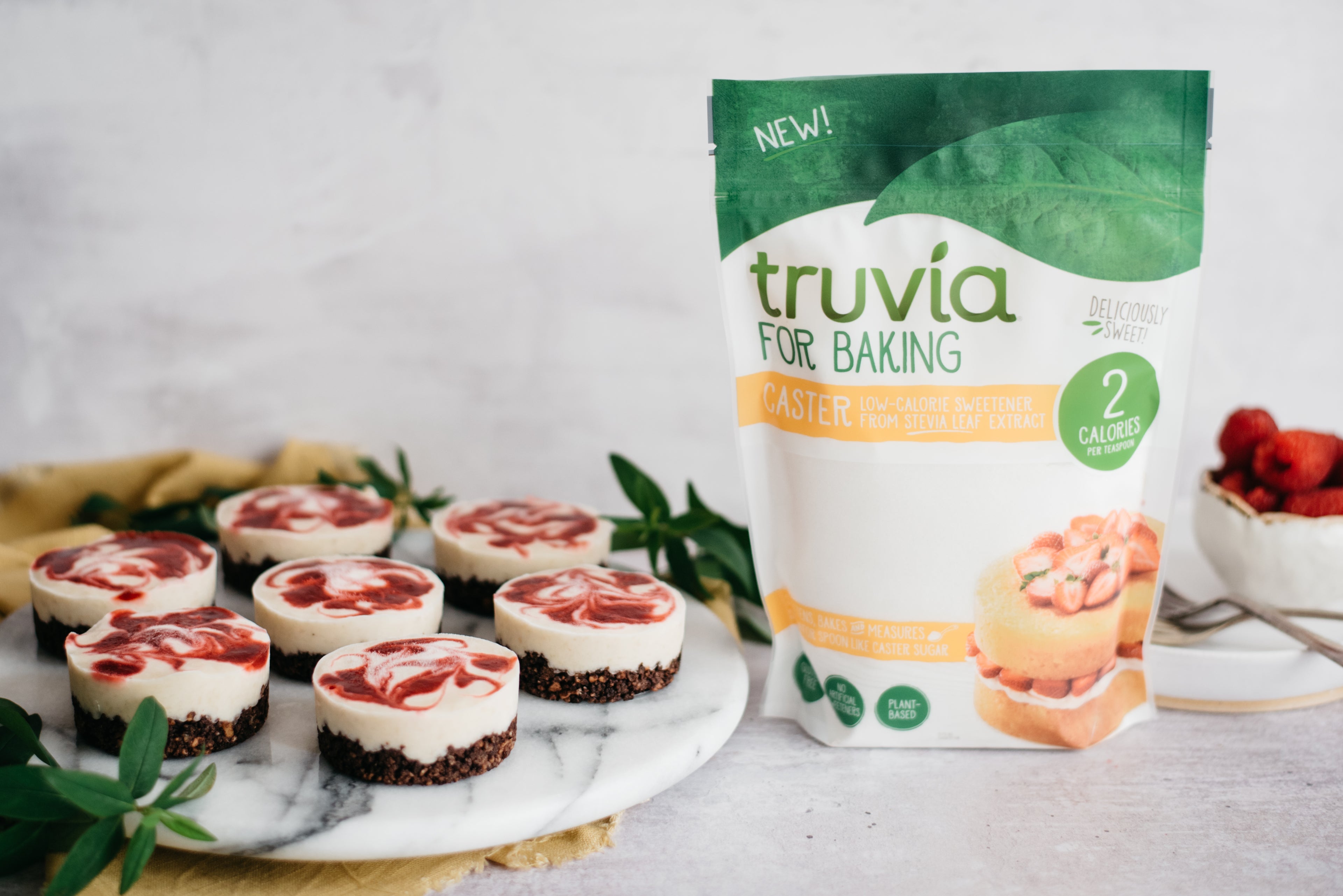 A plate of raspberry and banana cheesecake cups next to a pack of truvia for baking caster