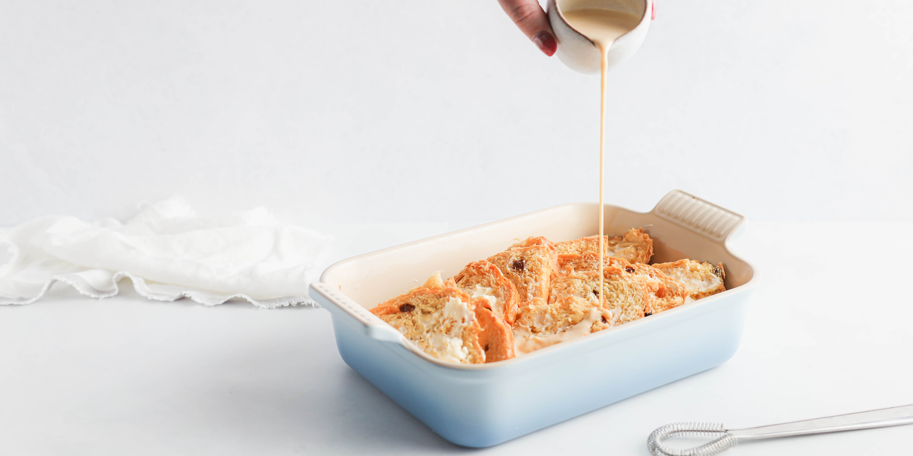 Panettone Bread & Butter Pudding being hand poured with cream ready to bake