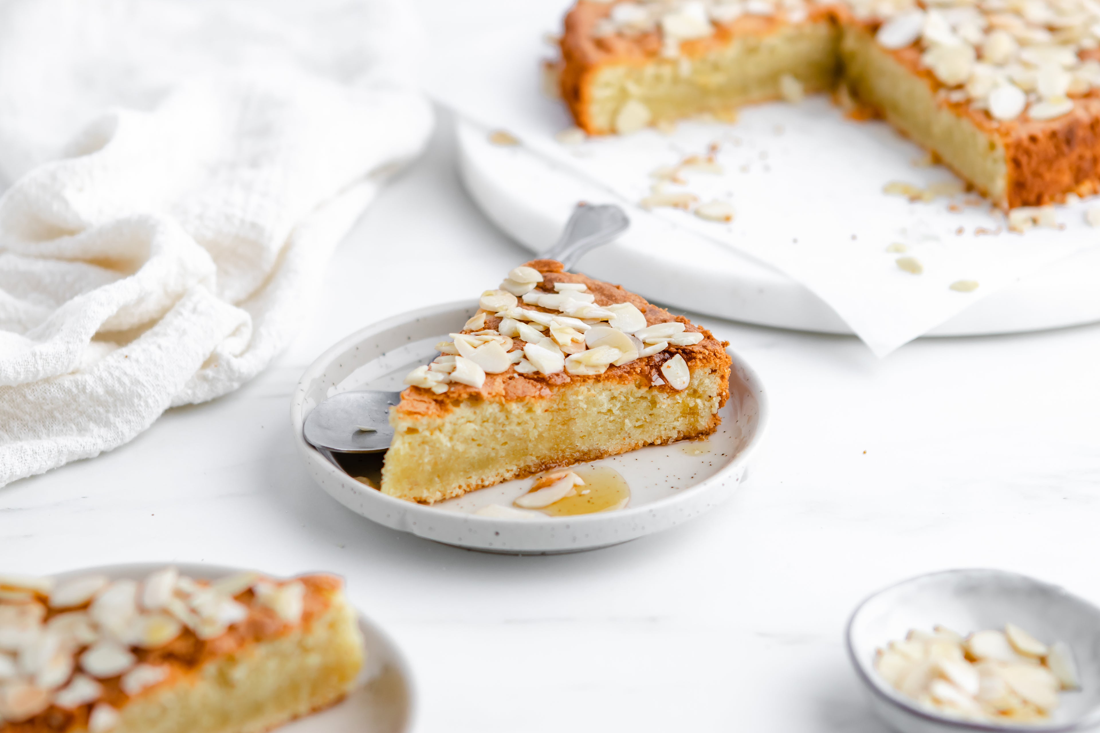 A slice of almond cake, with a drizzle of honey and a spoon
