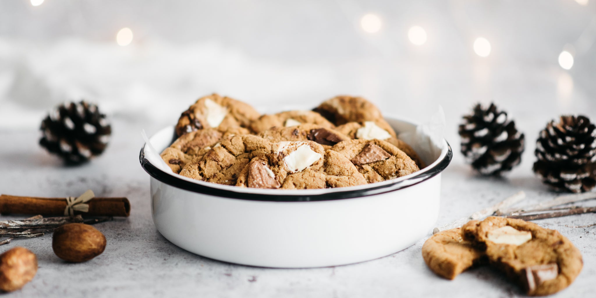 Bowl of cookies surrounded by pine cones and broken cookies
