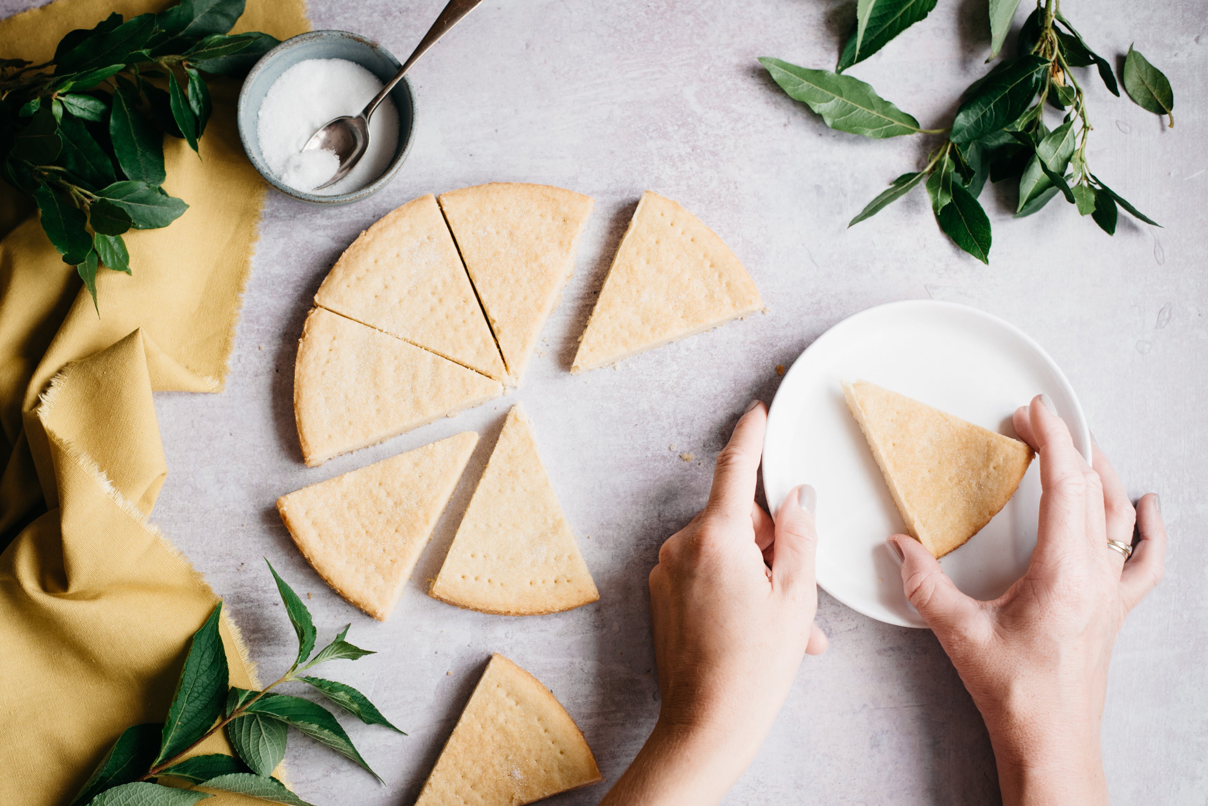 Top down view of a handing holding a slice of healthy shortbread on a plate