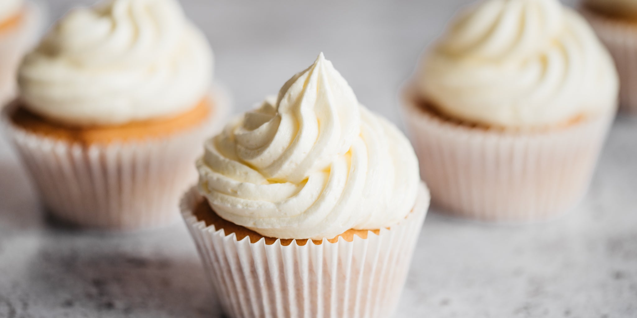 Close up of Vanilla Extract Cupcakes swirled with vanilla buttercream, with Nielsen Massey extract