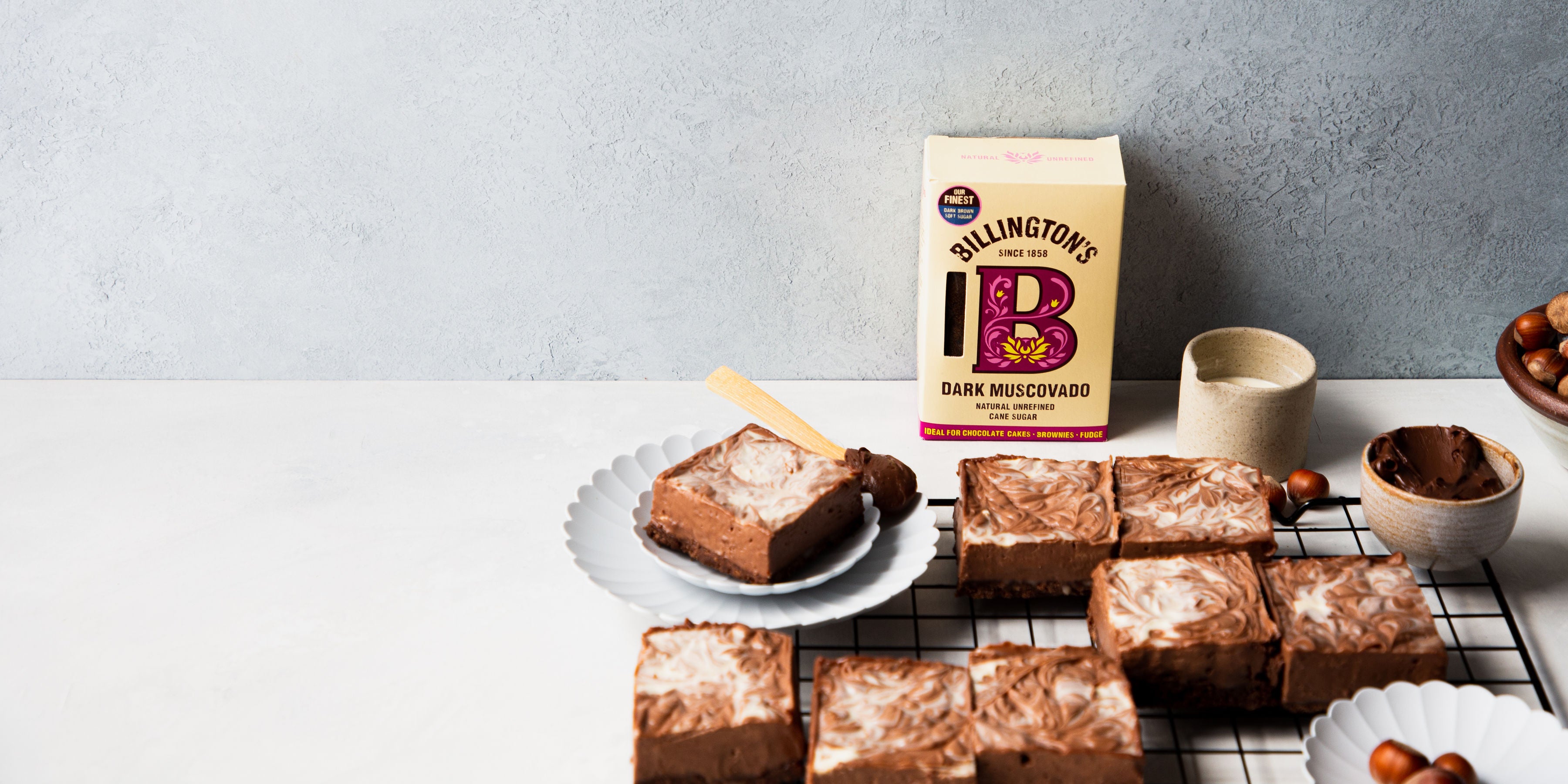 Nutella Cheesecake Bars on a wire rack with a box of Billington's Dark Muscovado