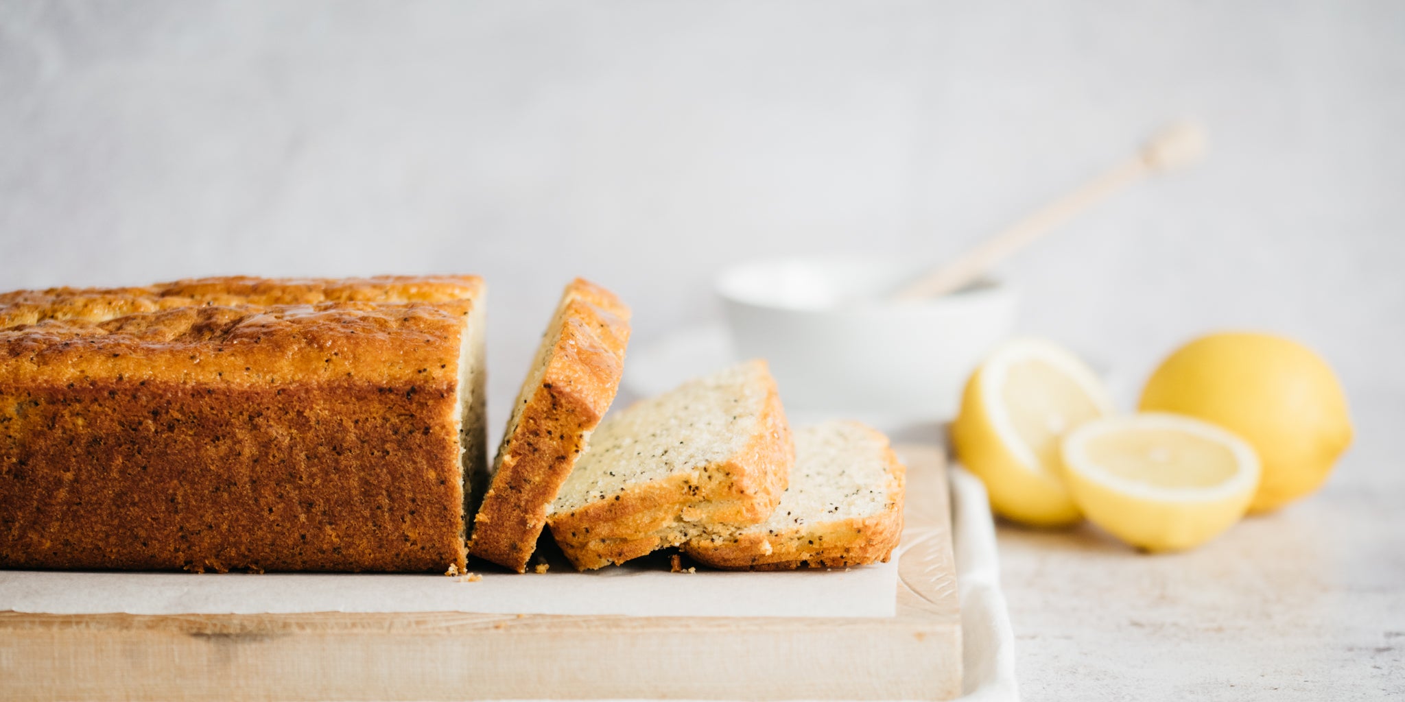 Lemon loaf on a chopping board with a few slices infront and some chopped lemon