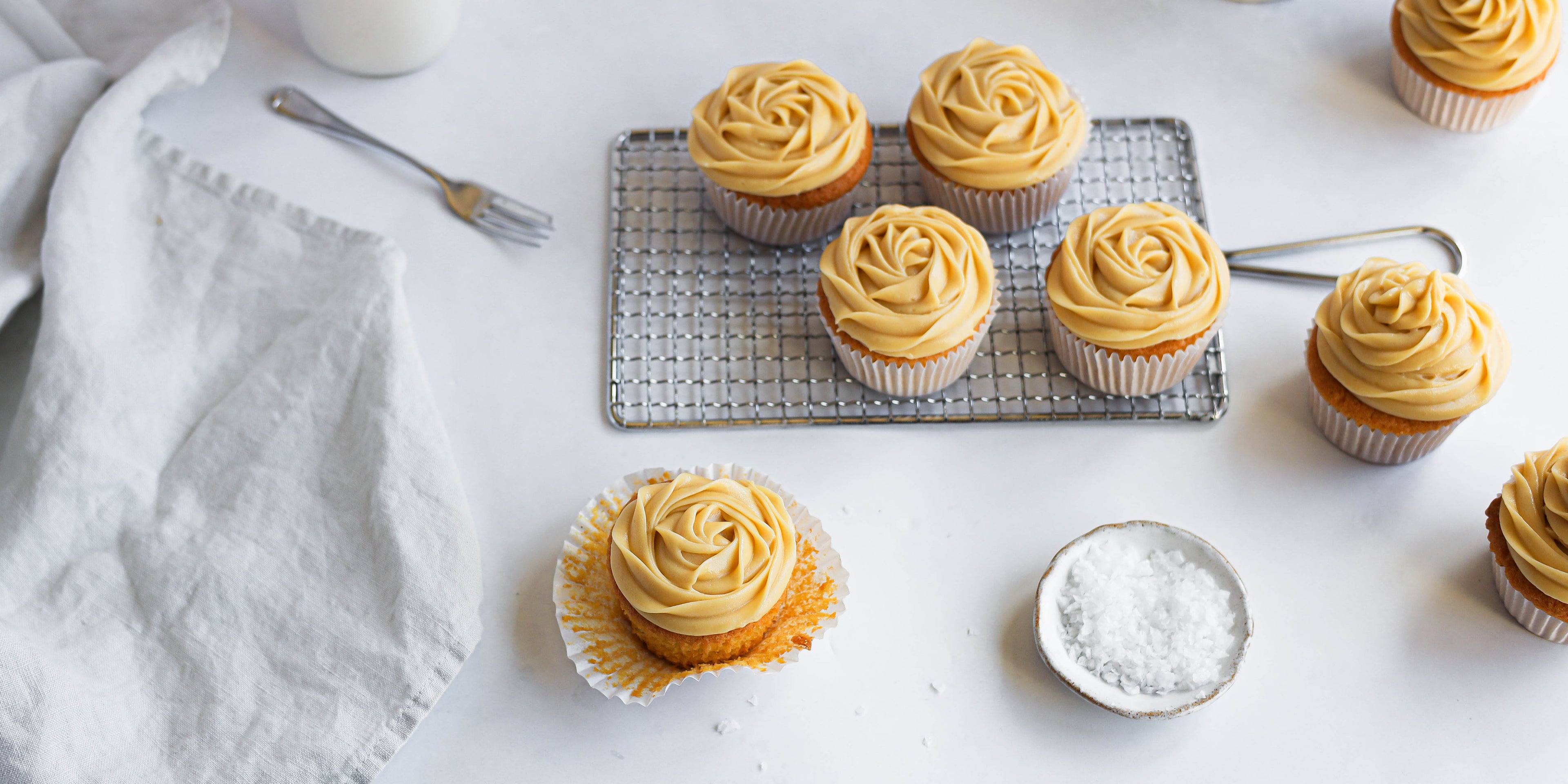 Top view of Salted Caramel Cupcakes on wire rack, with a cupcake out of its cupcake case