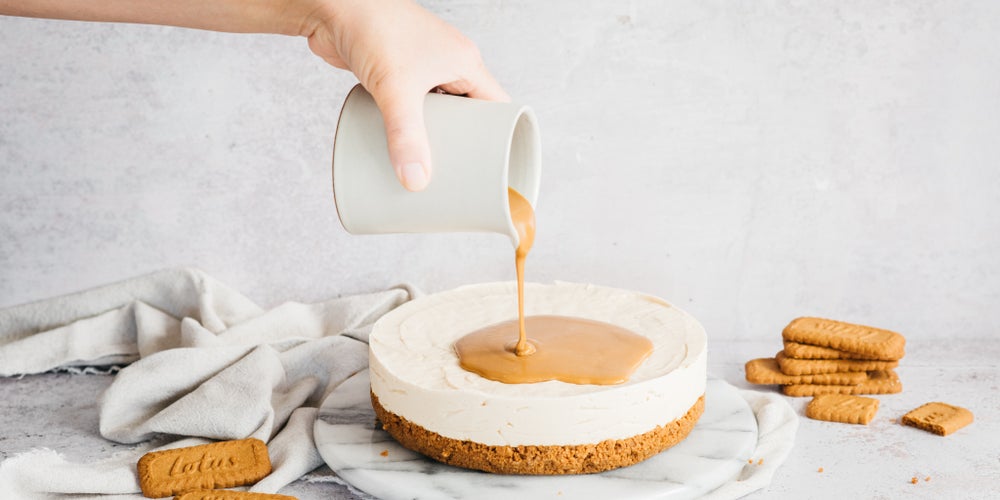 Hand pouring topping on to a cheesecake