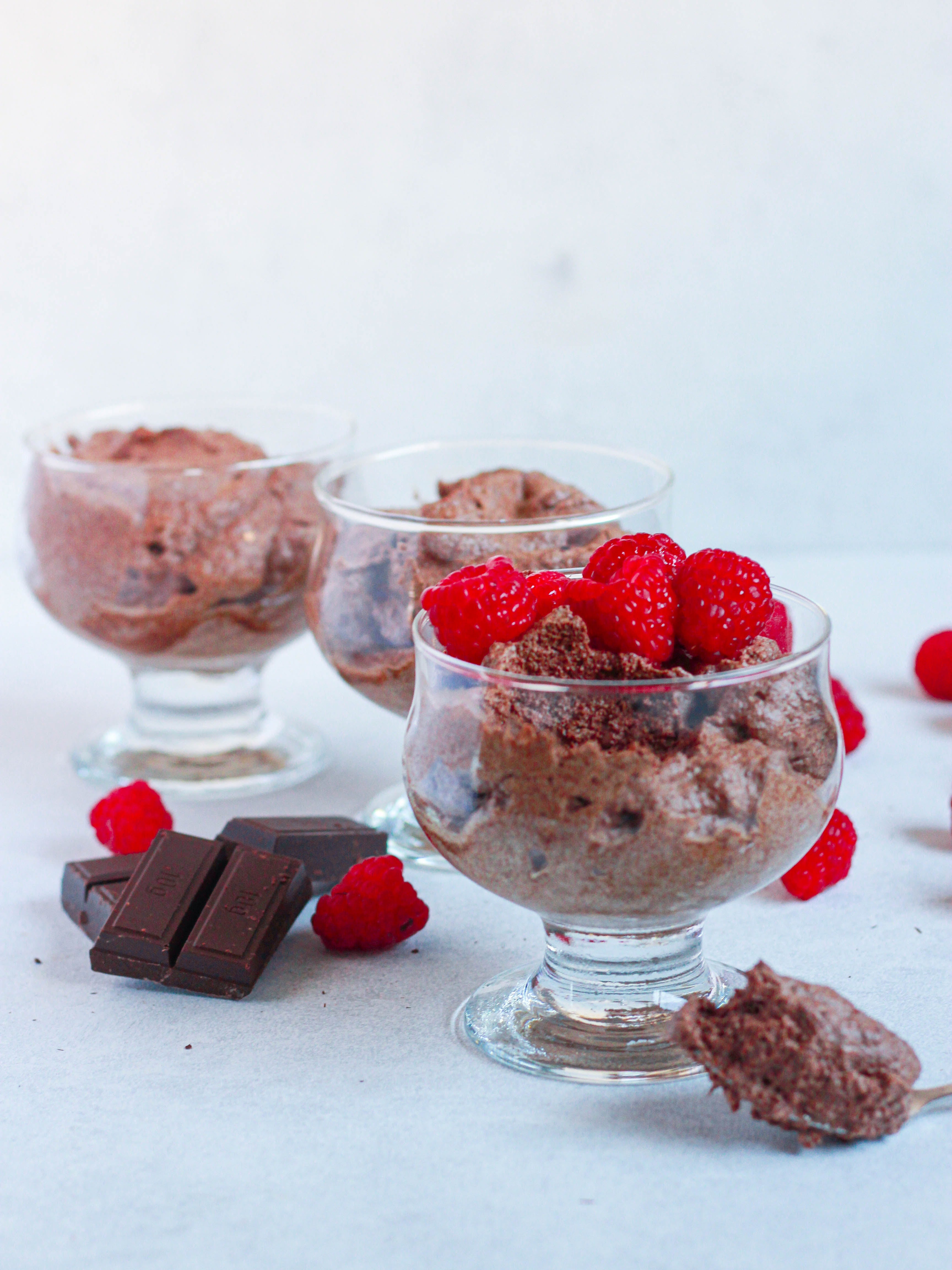 3 bowls of chocolate mousse, topped with raspberries and chocolate chunks