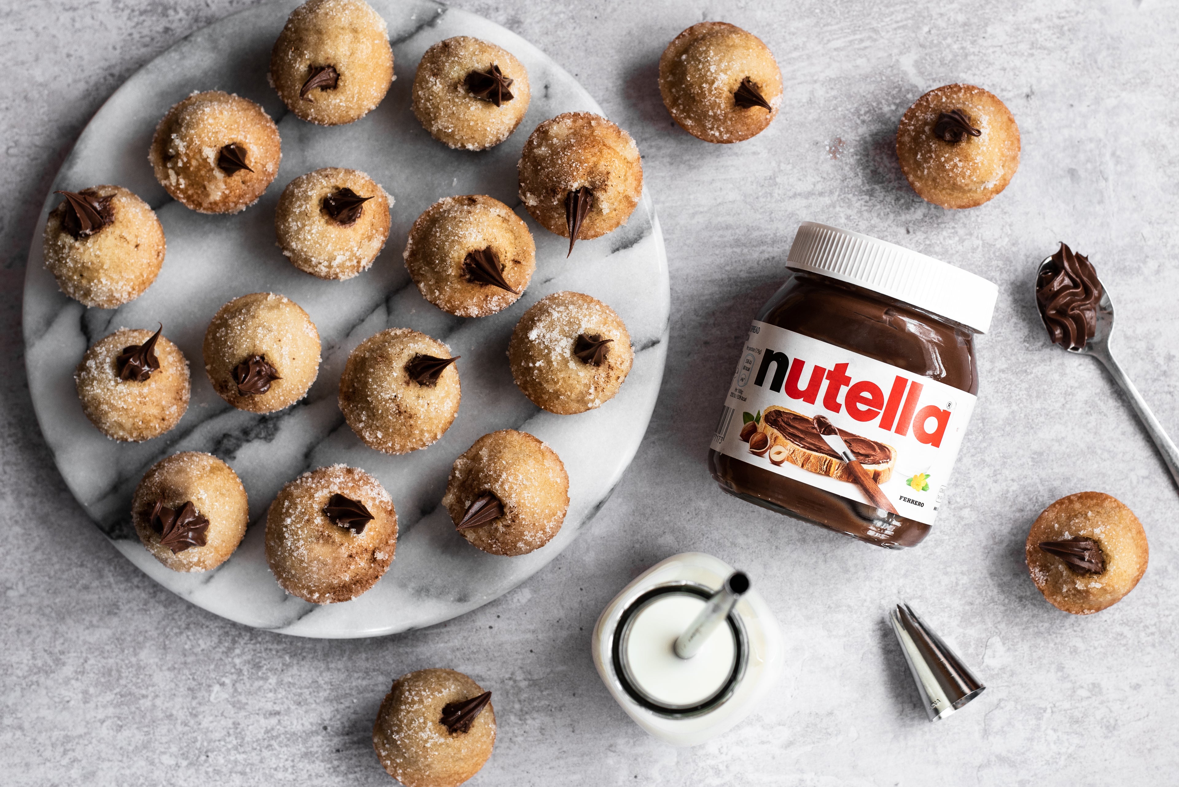 Plate of Nutella filled doughnuts next to a jar of Nutella