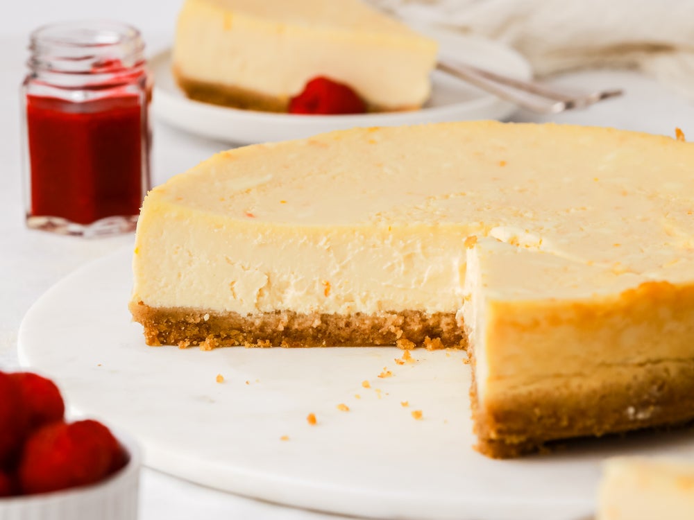 Side view of a baked vanilla cheesecake on a white plate