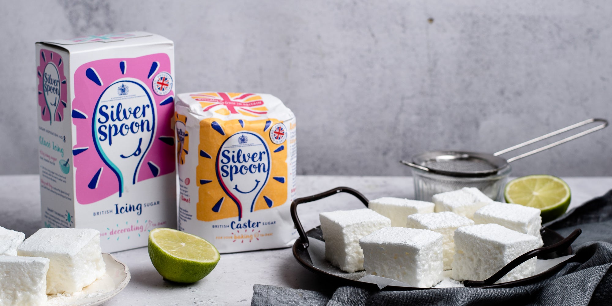 Gin & Tonic Marshmallows next to Silver Spoon Caster and Icing sugar, with sliced lime