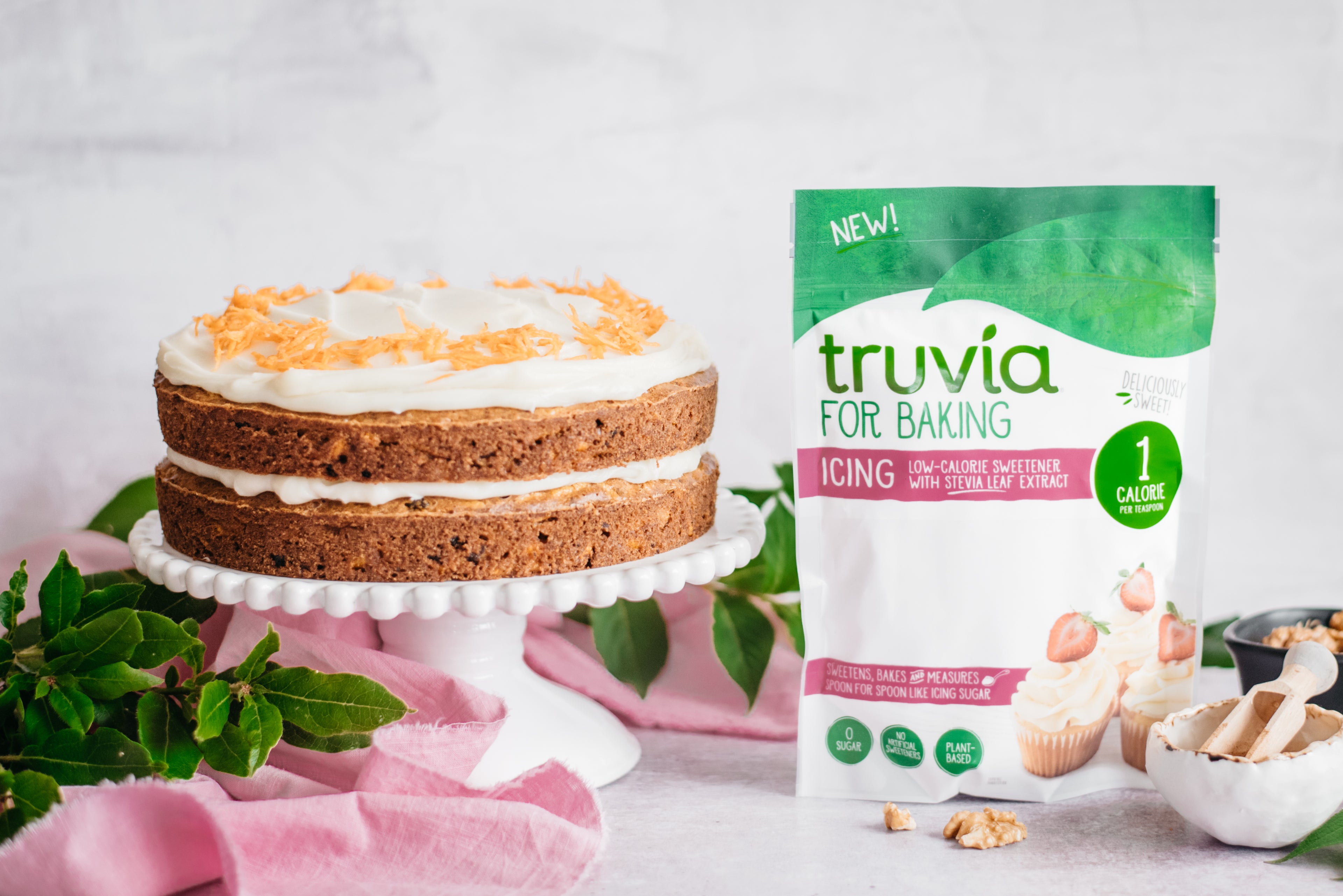 Side on view of a low sugar carrot cake next to a pack of truvia for baking icing