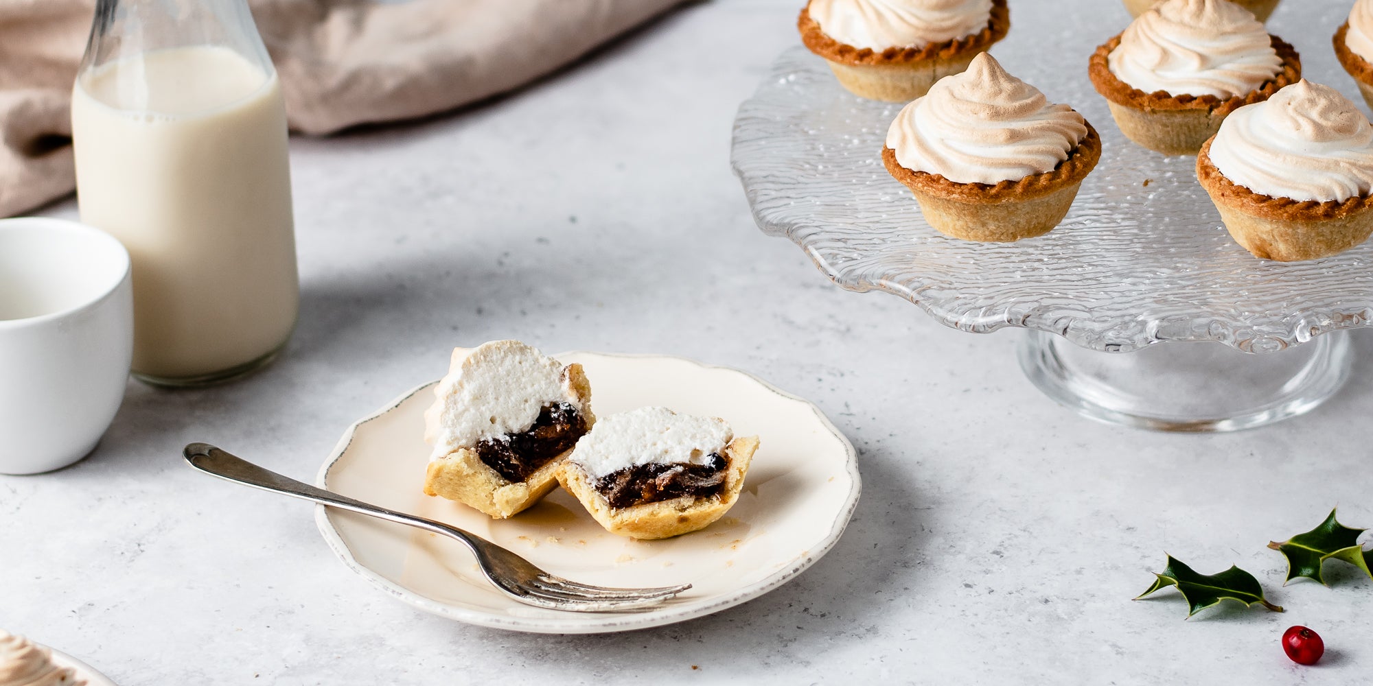 Meringue Topped Mince Pie sliced in half on a plate showing the inside filled with mincemeat and meringue next to a fork