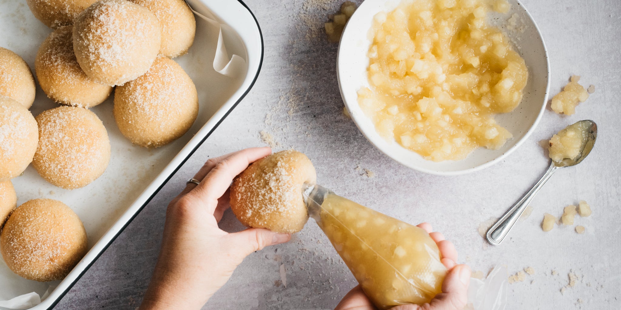 Apple filling being piped into a doughnut