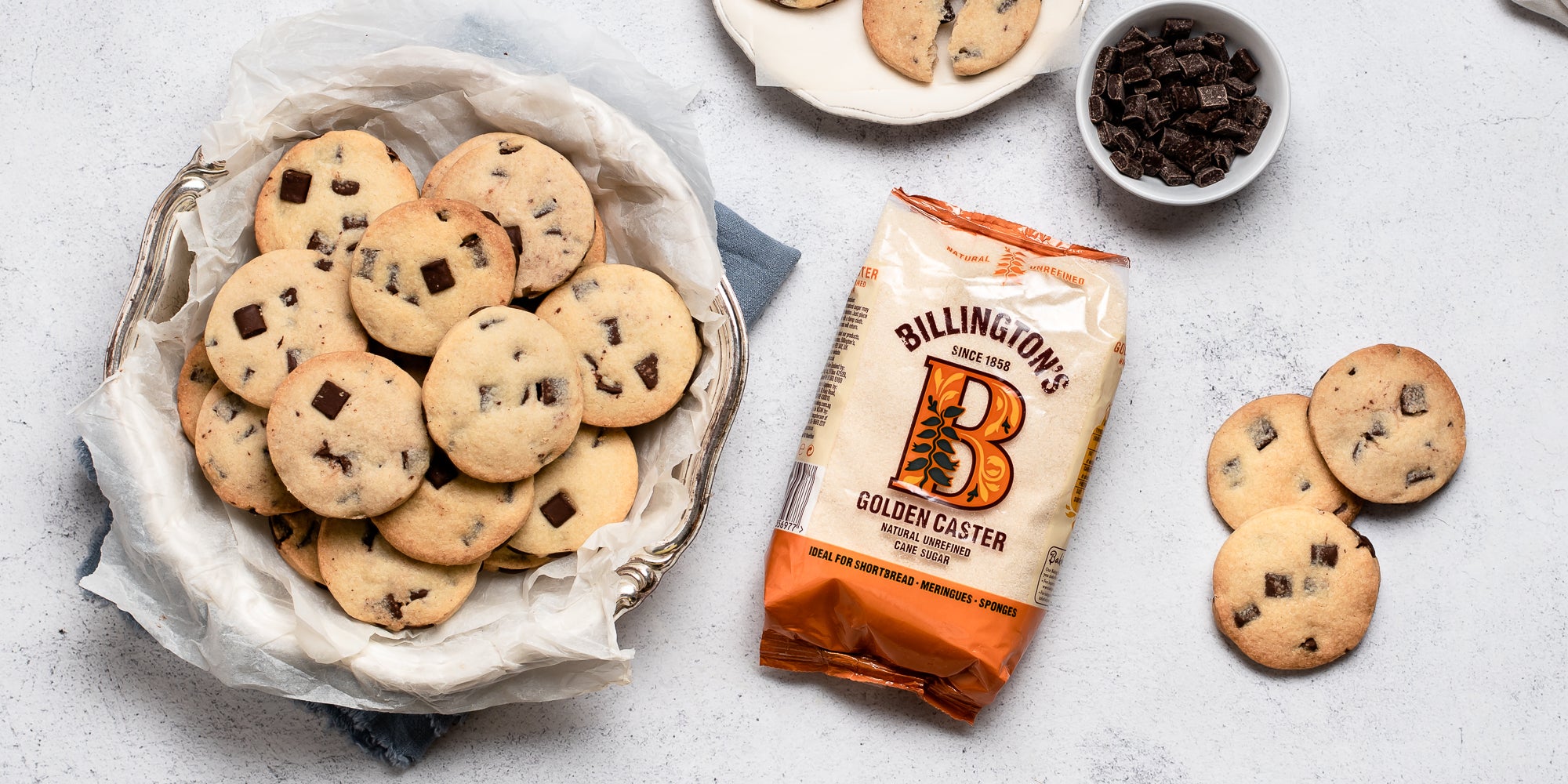 Top view of Chocolate Chunk Shortbread in a cookie jar, next to a bag of Billington's golden caster sugar