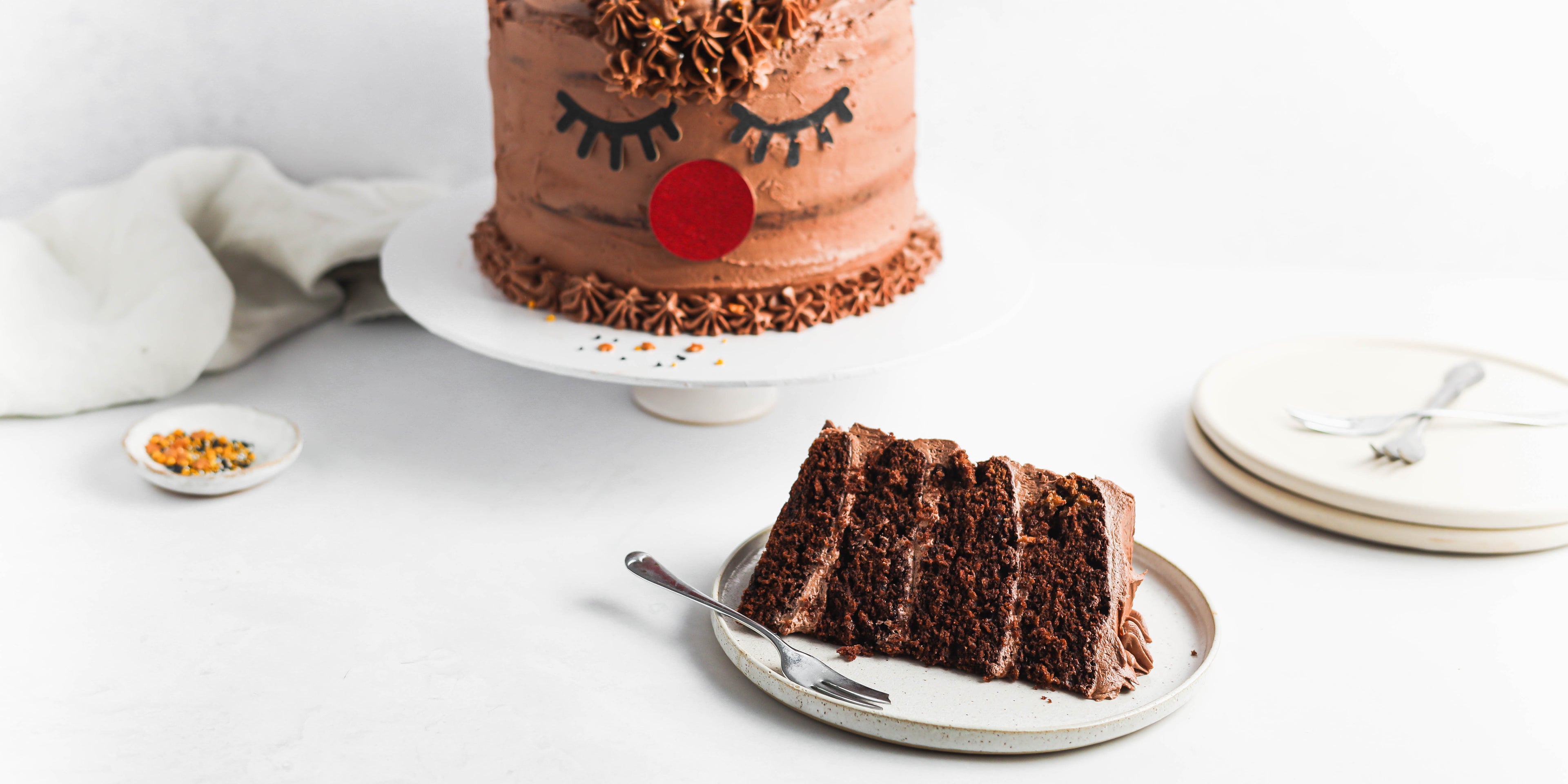 Christmas Reindeer Cake with a slice cut out showing four chocolate cake layers with chocolate butter cream