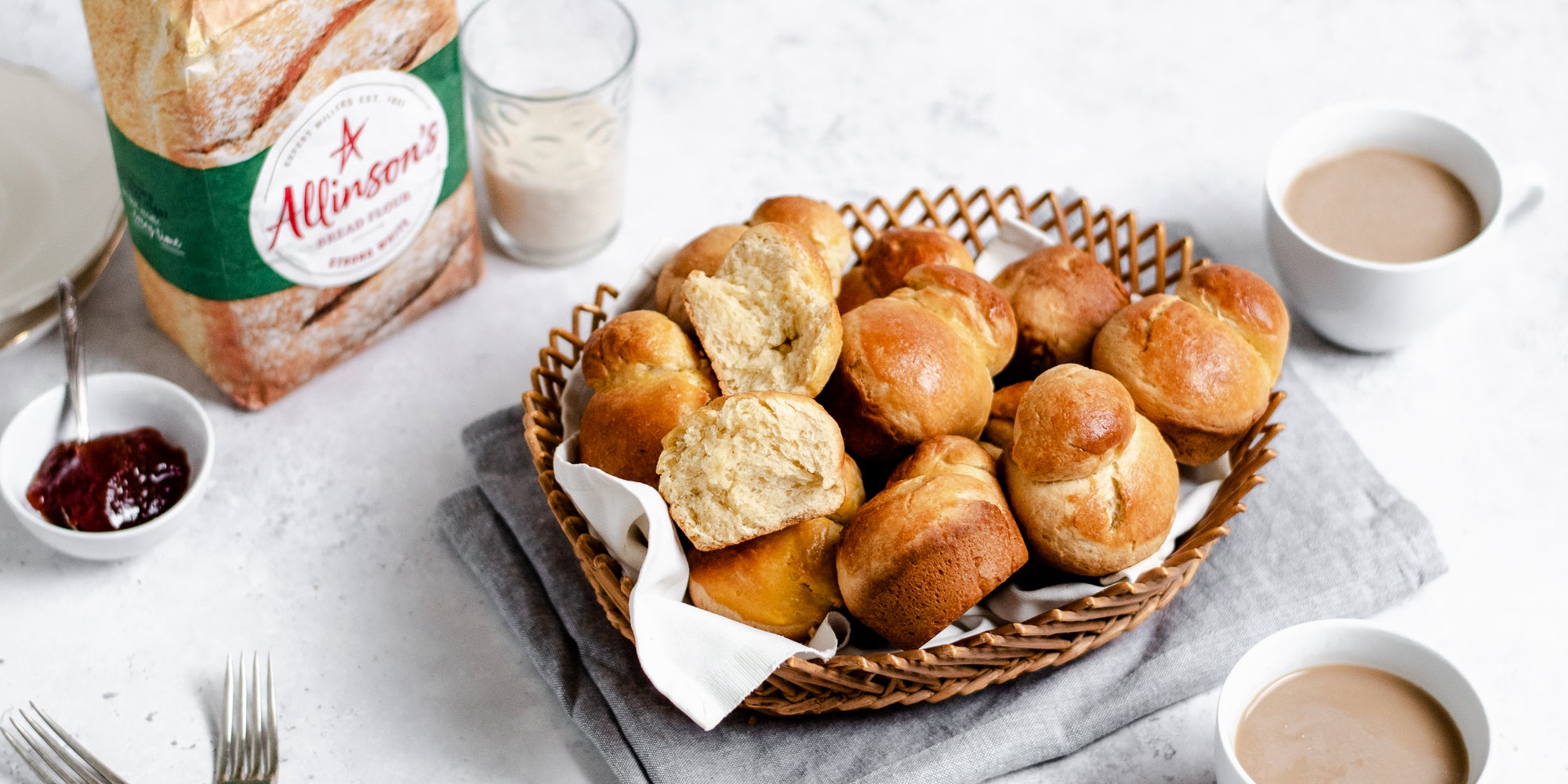 Basket of a batch of Brioche, next to a bag of Allinson's strong white flour. Cups of tea in the background and foreground