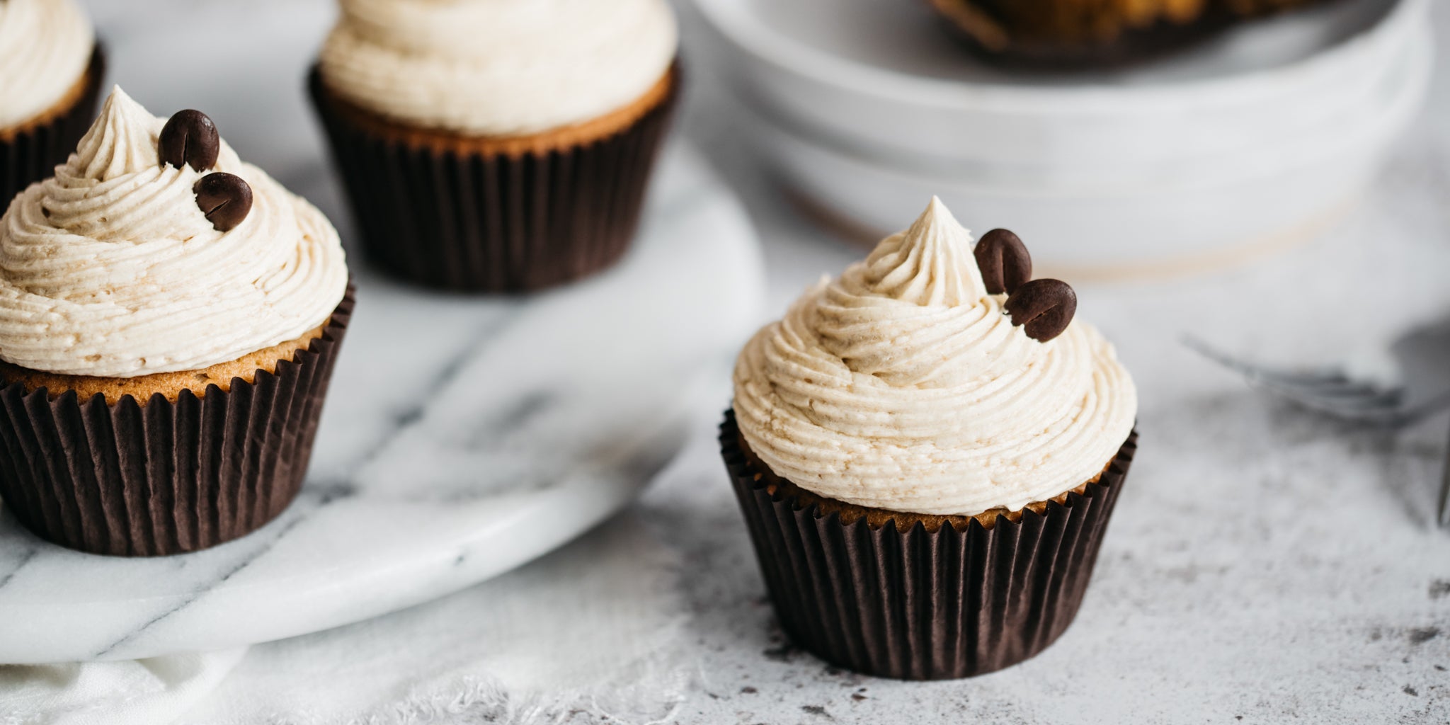 Close up of Coffee Cupcakes whirled with coffee buttercream and topped with coffee beans