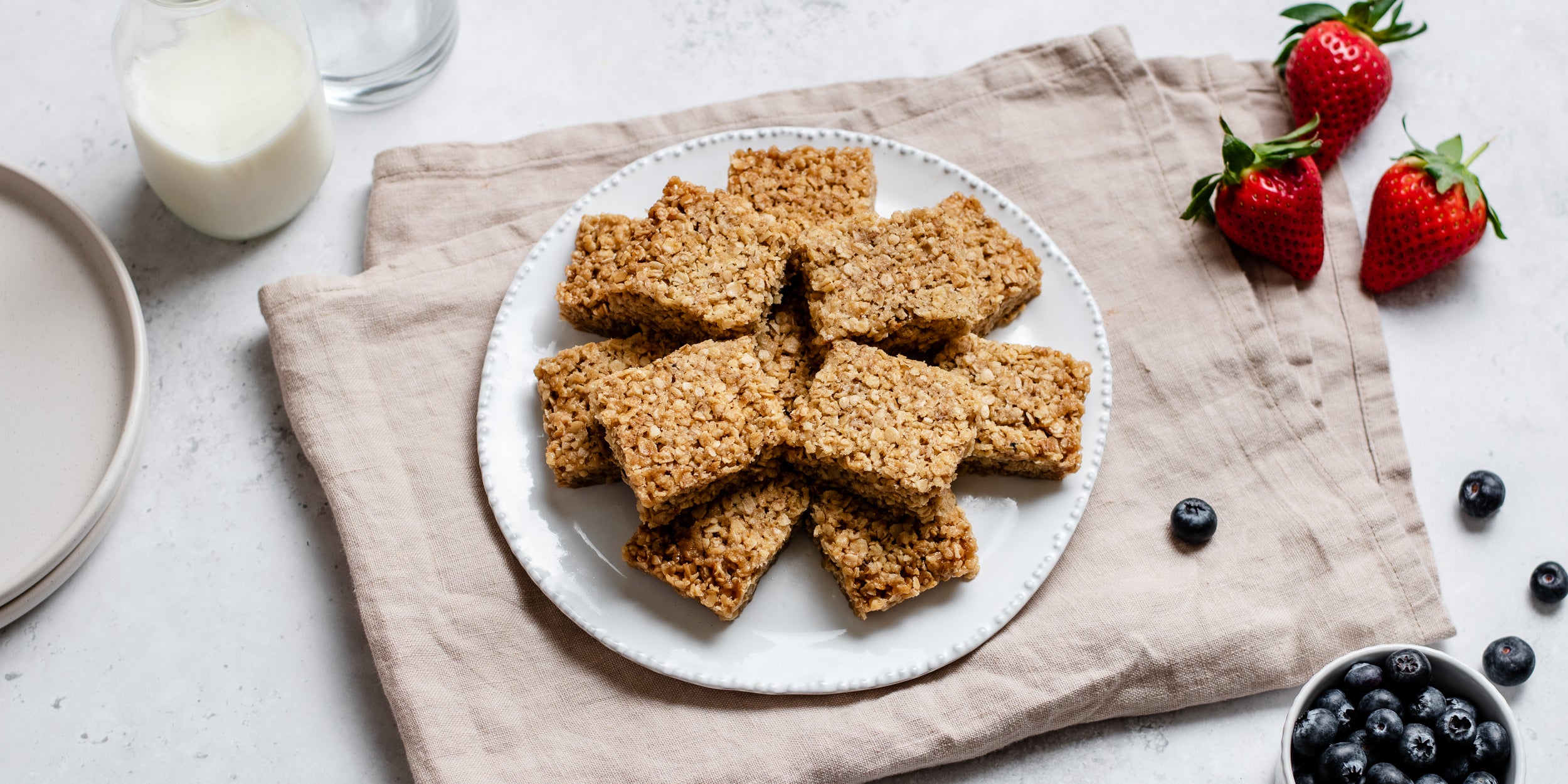 Easy Flapjack served on a plate, next to fresh berries and glass of milk