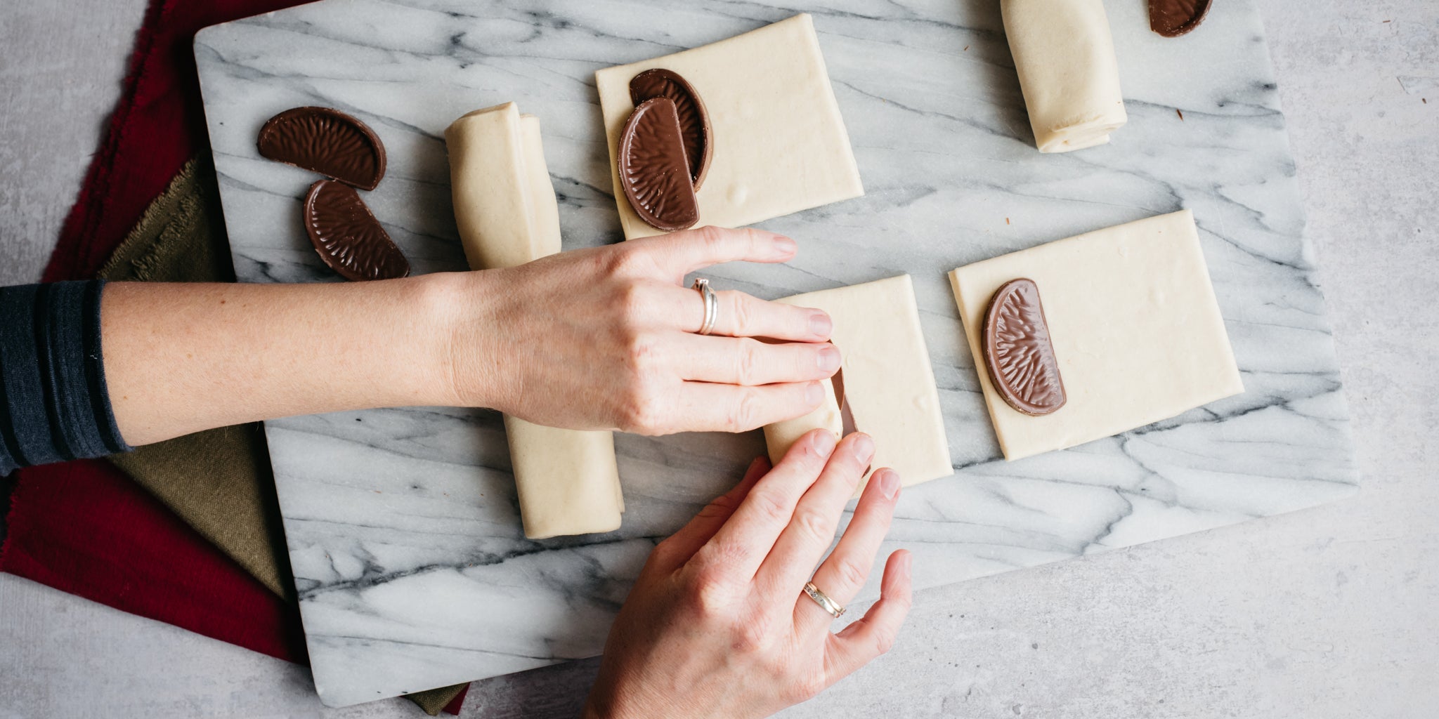 Hands rolling a piece of terrys chocolate orange into dough