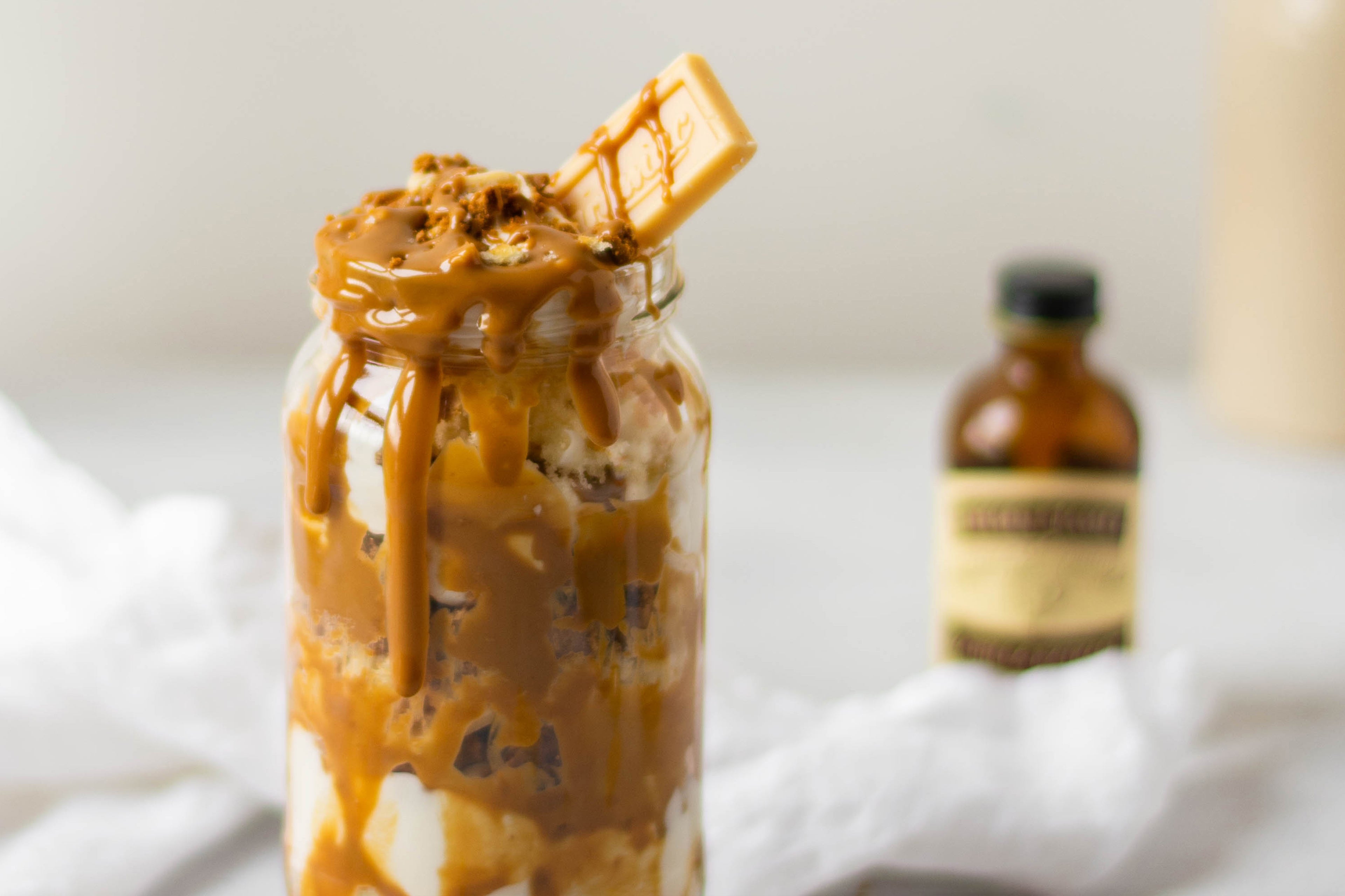 Close up of Biscoff & Caramac Cake Jar, with a bottle of Nielsen-Massey Vanilla Extract in the background
