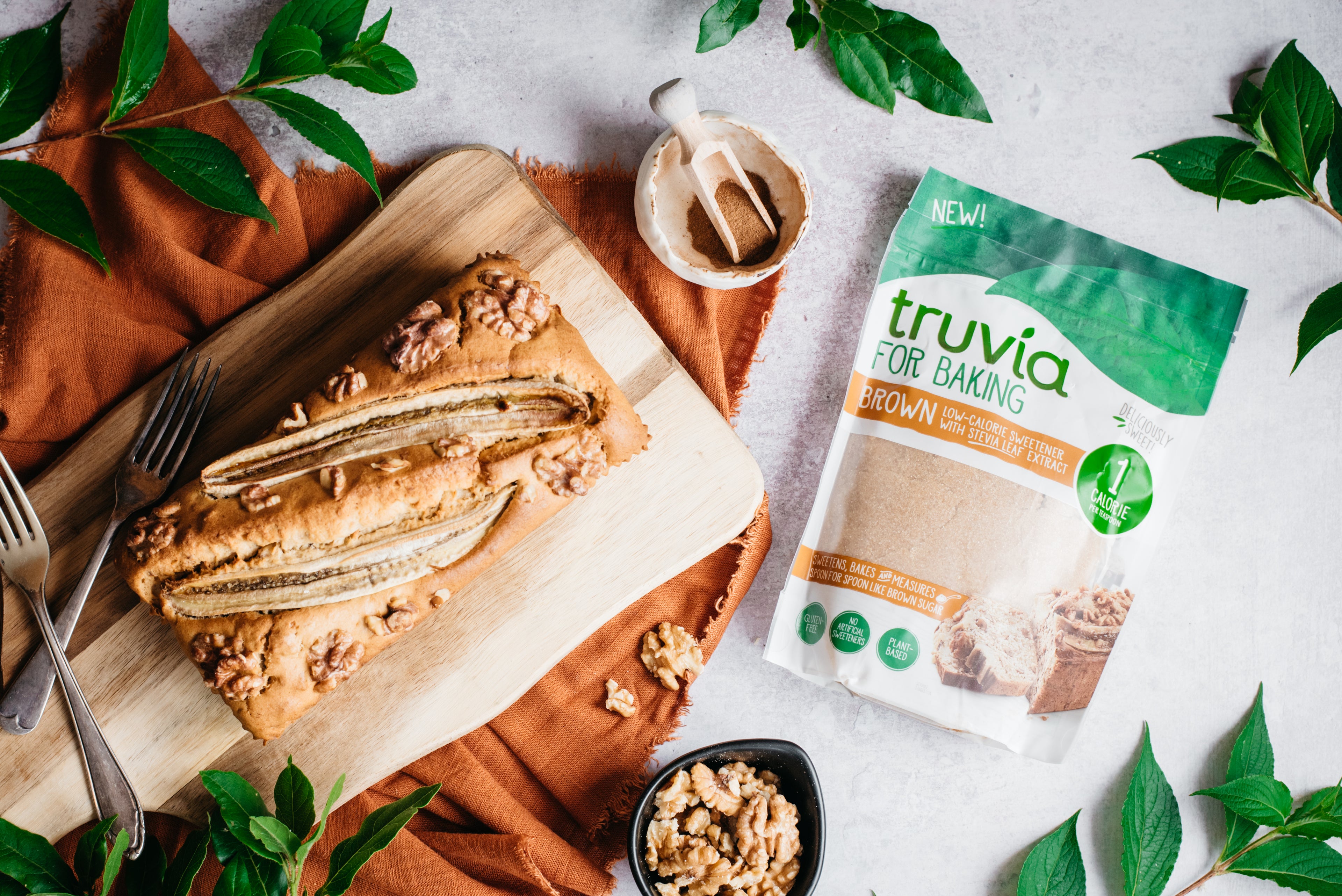 A top down view of a loaf of healthy banana bread next to a pack of truvia for baking brown sugar substitute