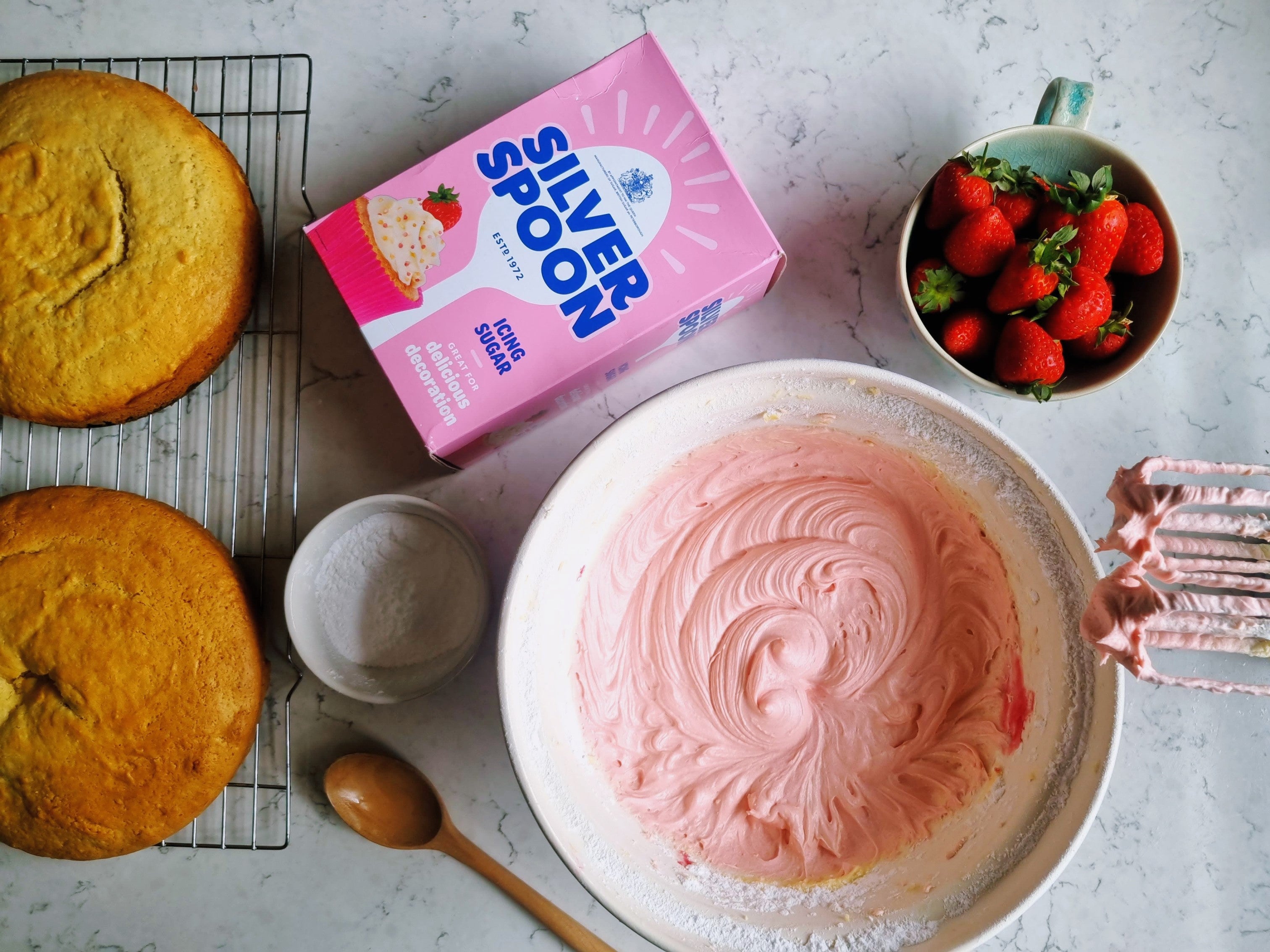 Bowl of fresh strawberry buttercream being mixed for two sponge cakes 