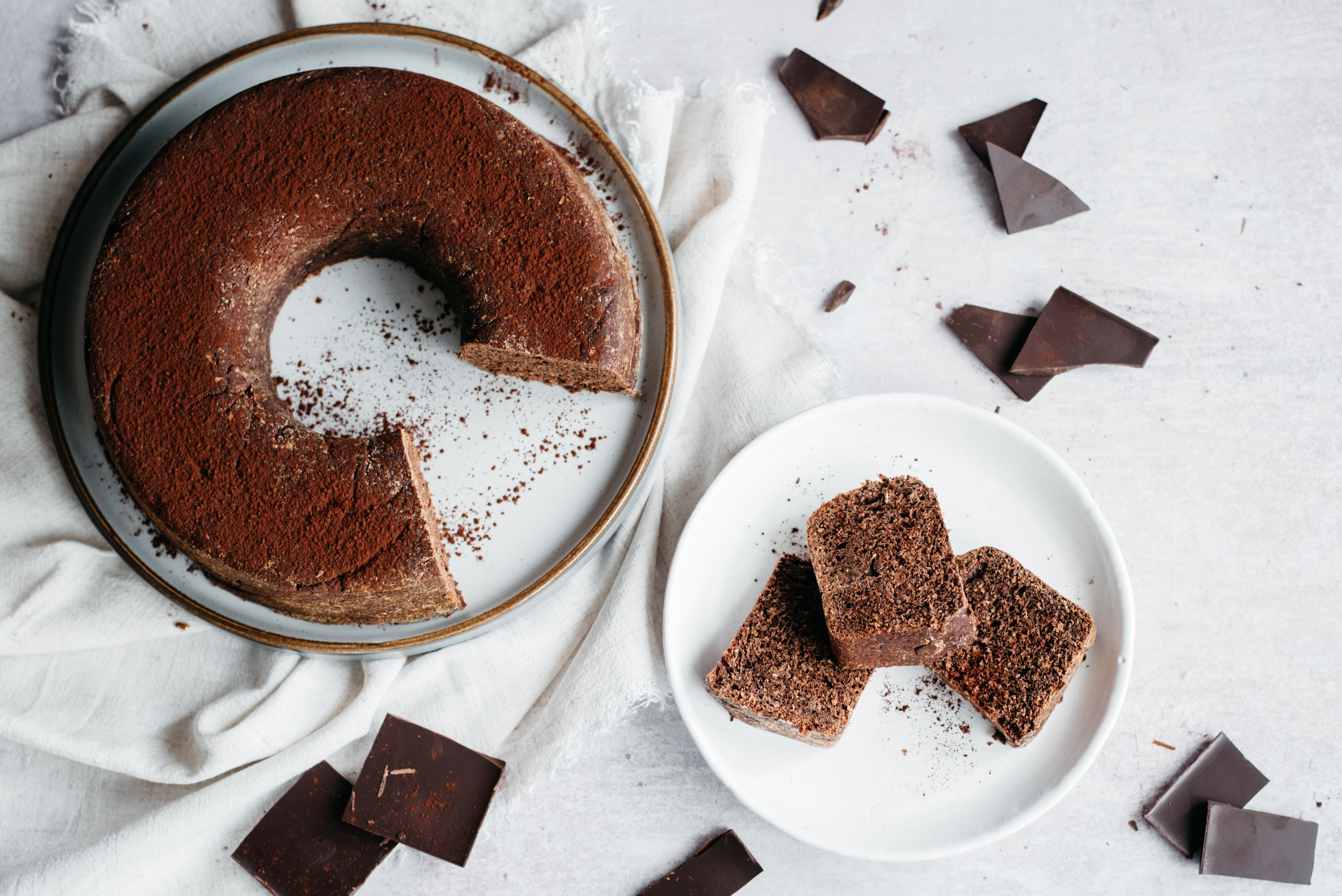 Top view of Chocolate Bread, with slices on a plate, dusted in cocoa powder.