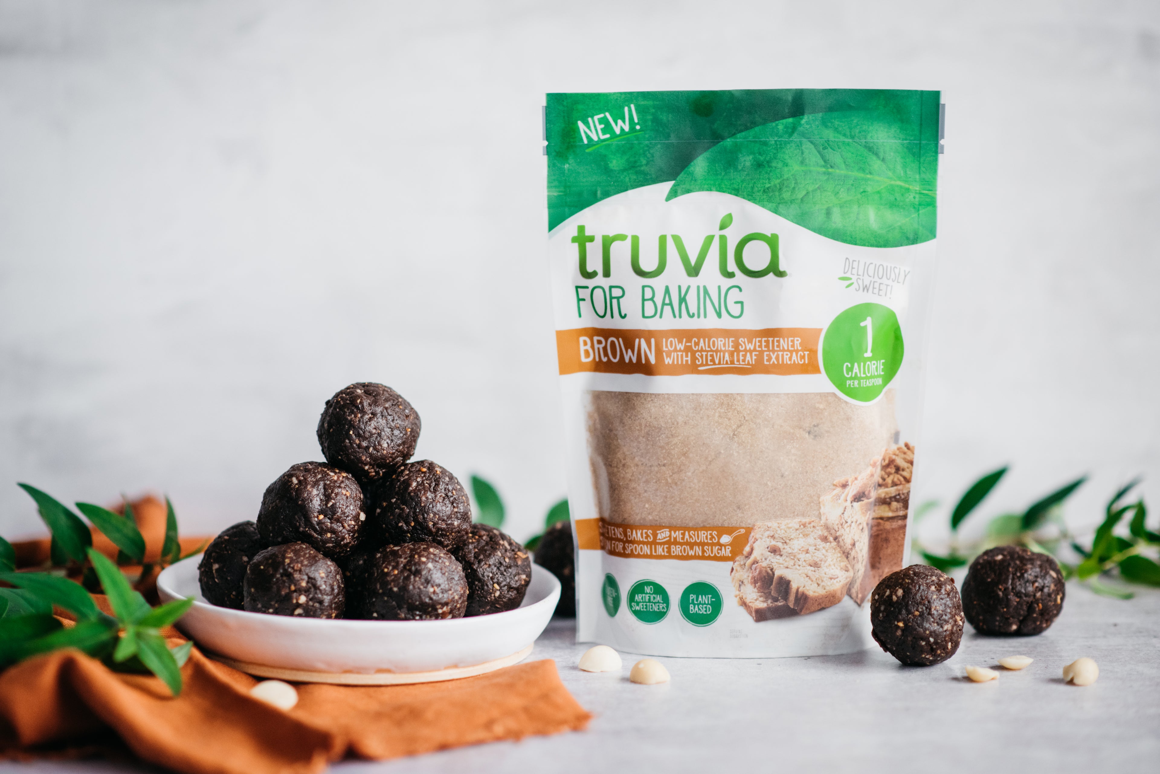 A bowl of raw energy balls next to a packet of Truvia for baking brown