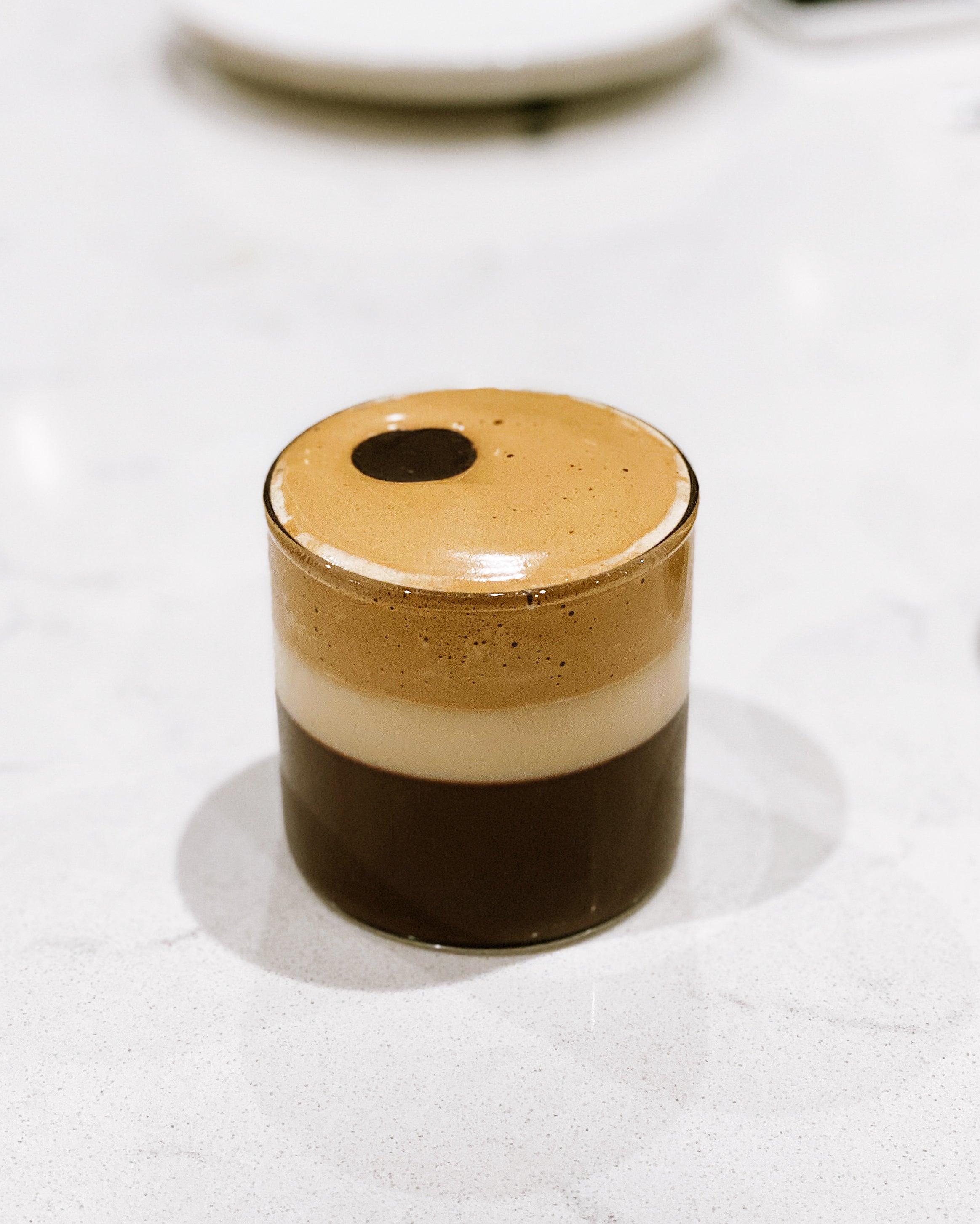 Layered Dalgona coffee with a frothy top in a small glass 