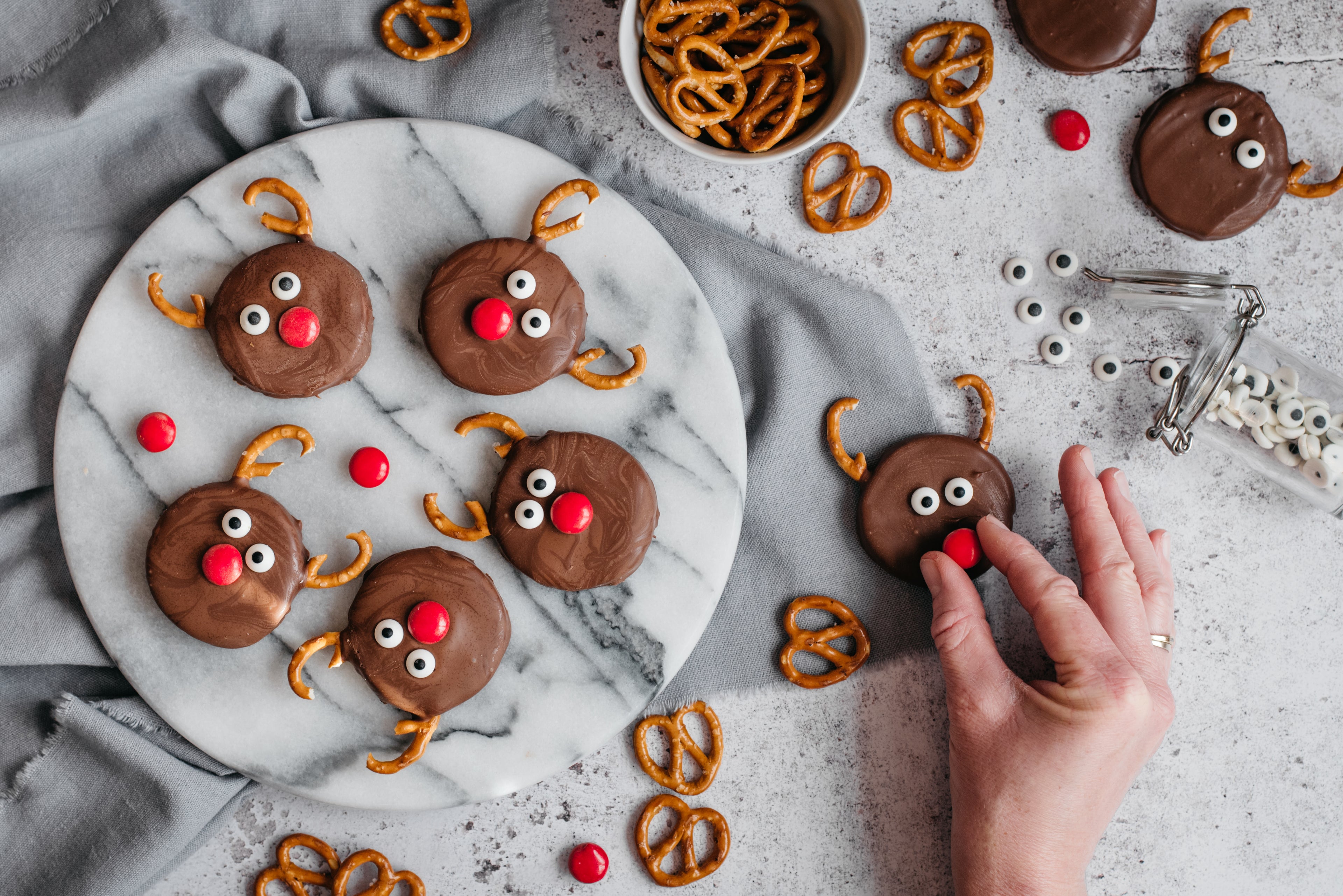 Reindeer Orange Creams being hand decorated with pretzels and red smarties for Rudolph's nose