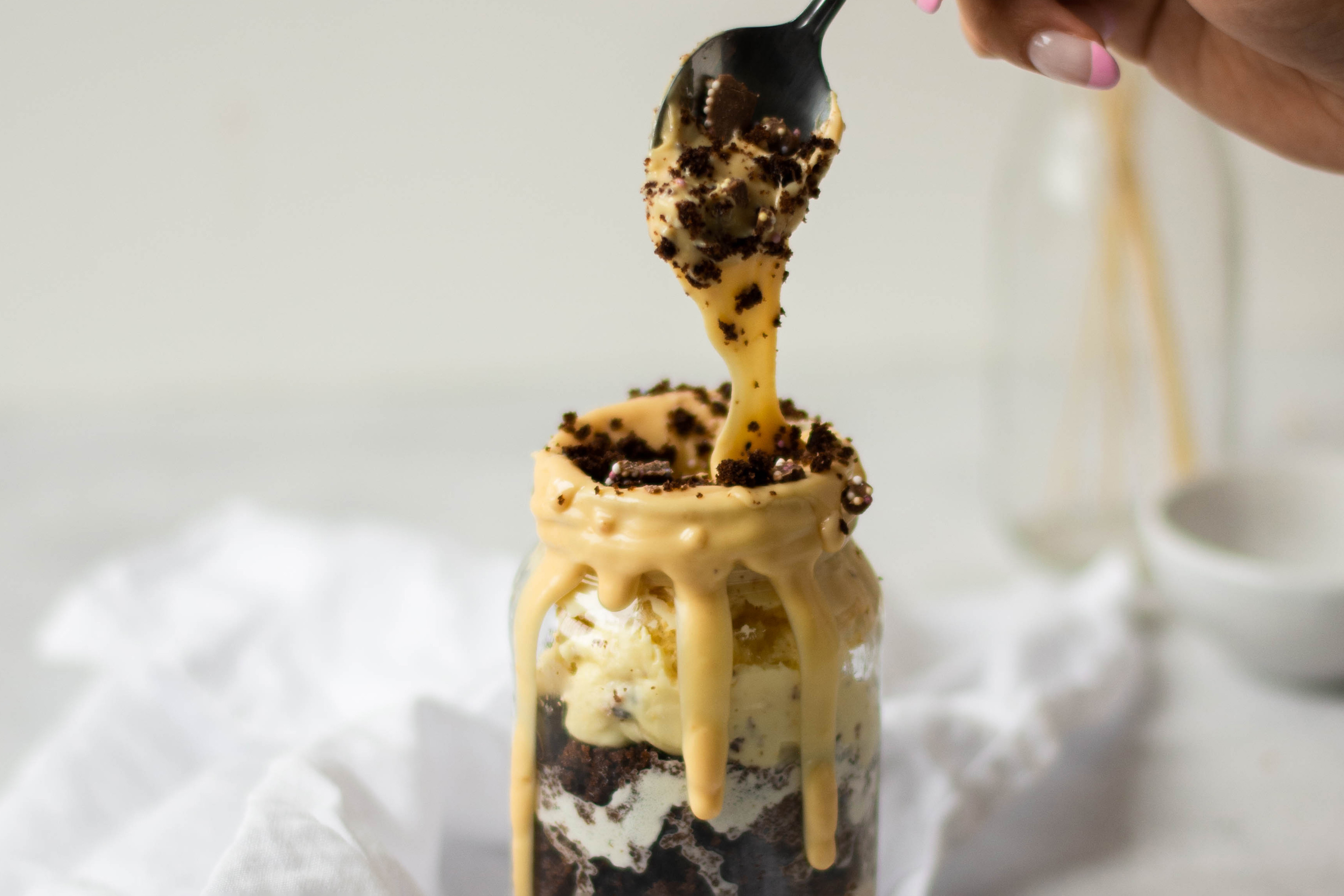 Close up of spoon dipping into the gooey chocolate in a Bailey Jar Cake. Hand holding the spoon.
