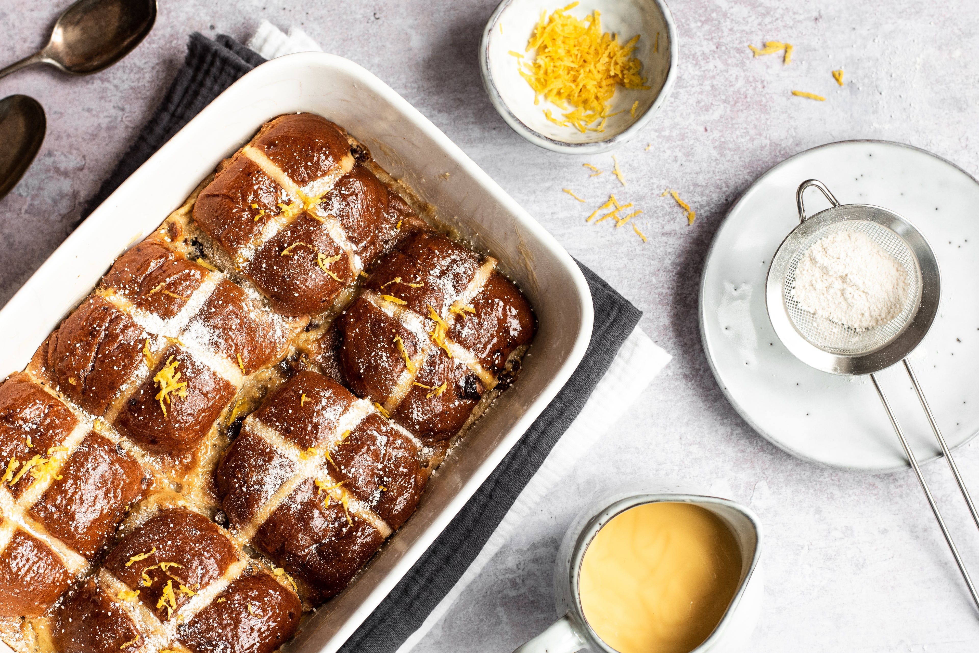 A tray-bake of Hot Cross Bun Bread Butter Puddings at an angle