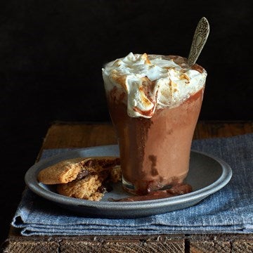 Hot chocolate in glass on a plate with a cookie