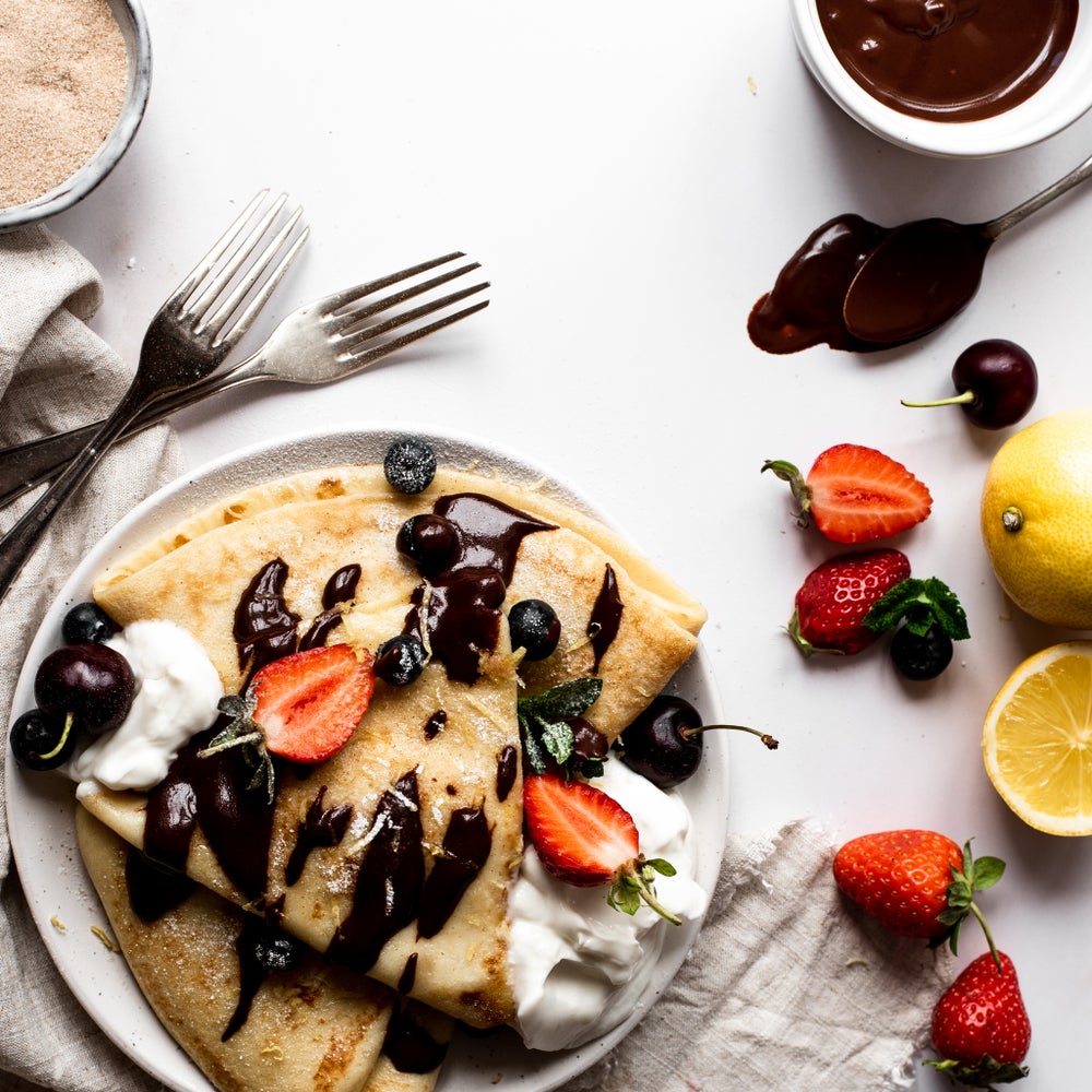 Pancakes with a cream, black cherry and strawberry topping, dusted with icing sugar