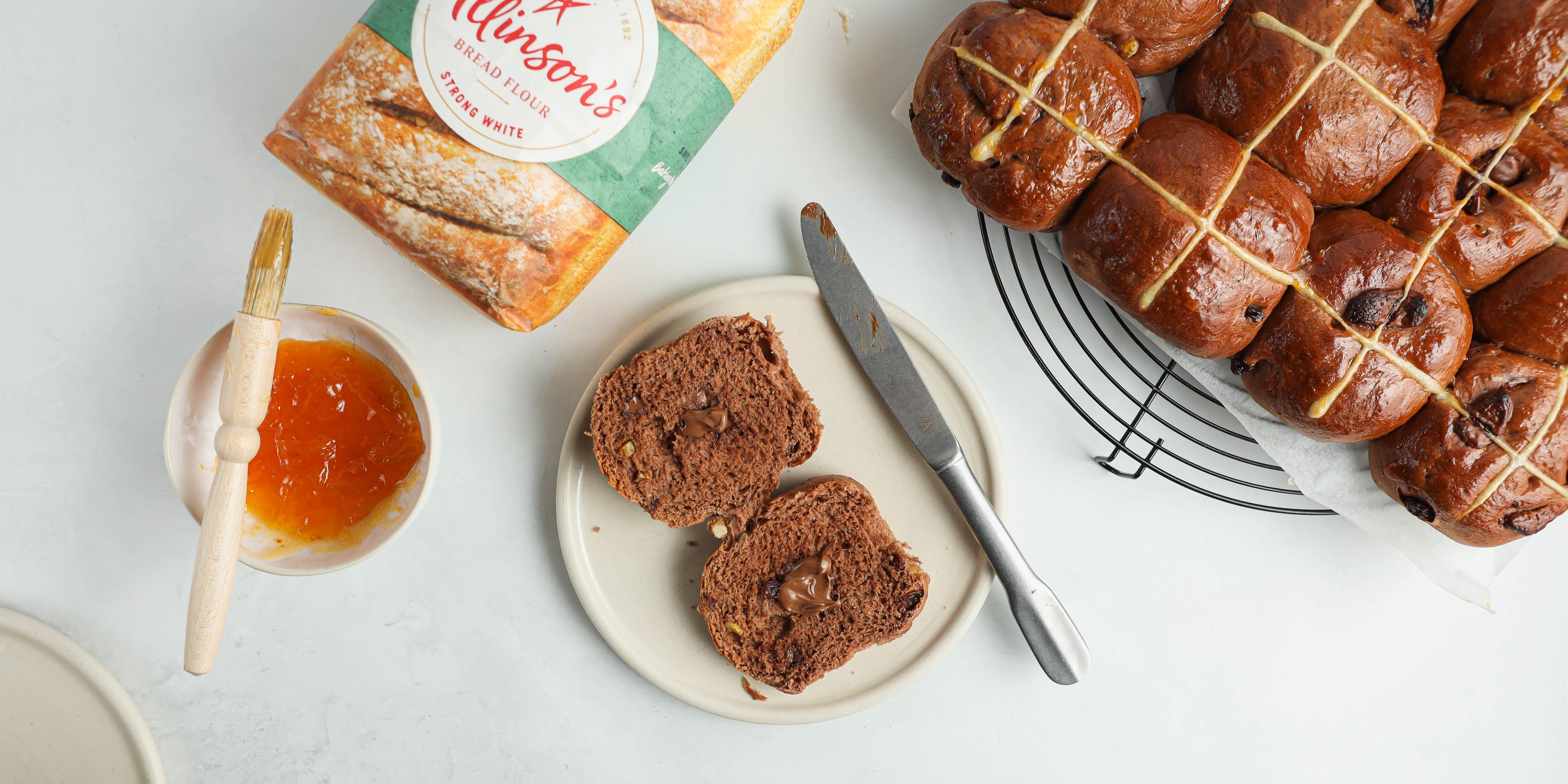 Top view of Chocolate Hot Cross Buns being cut in half and ready to butter