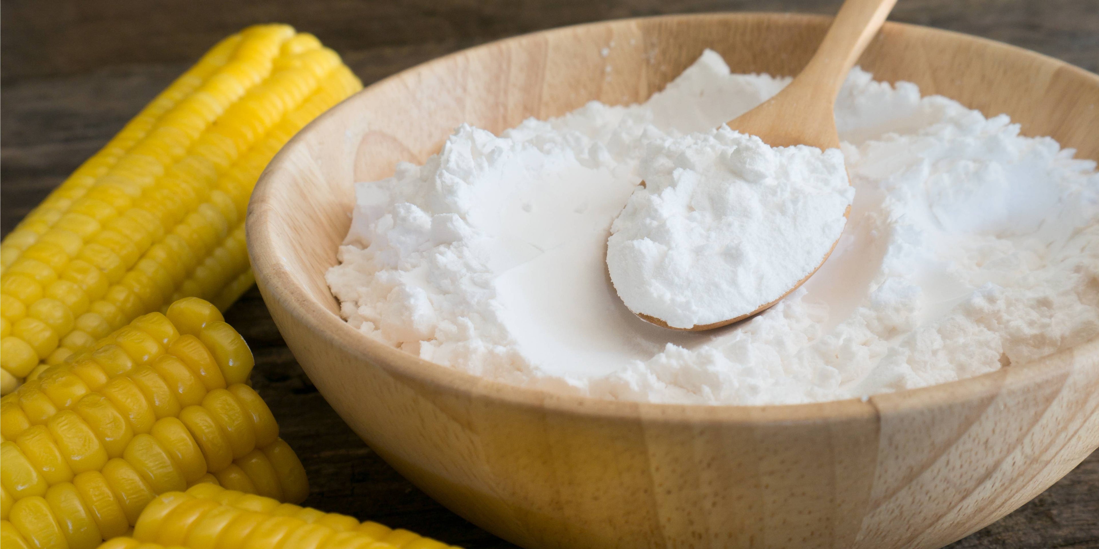 Cornflour in a wooden bowl next to an ear of corn