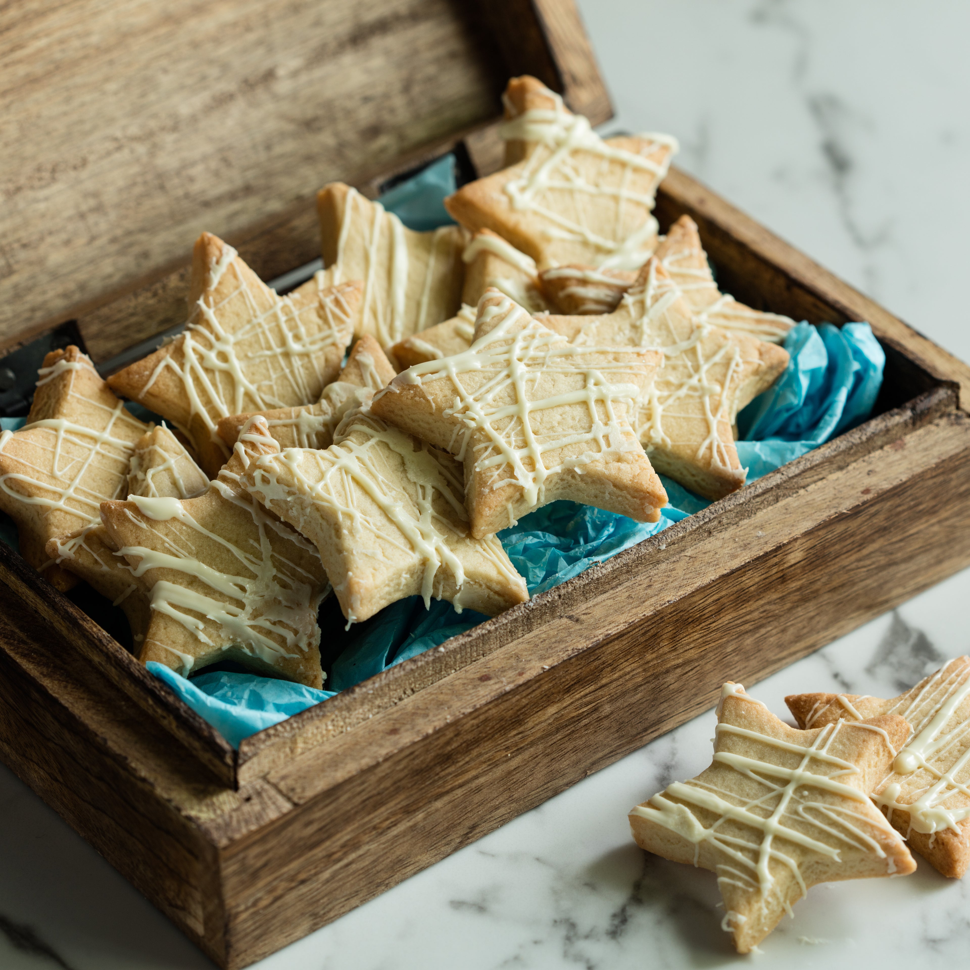 Star shaped biscuits inside a wooden box with blue tissue paper