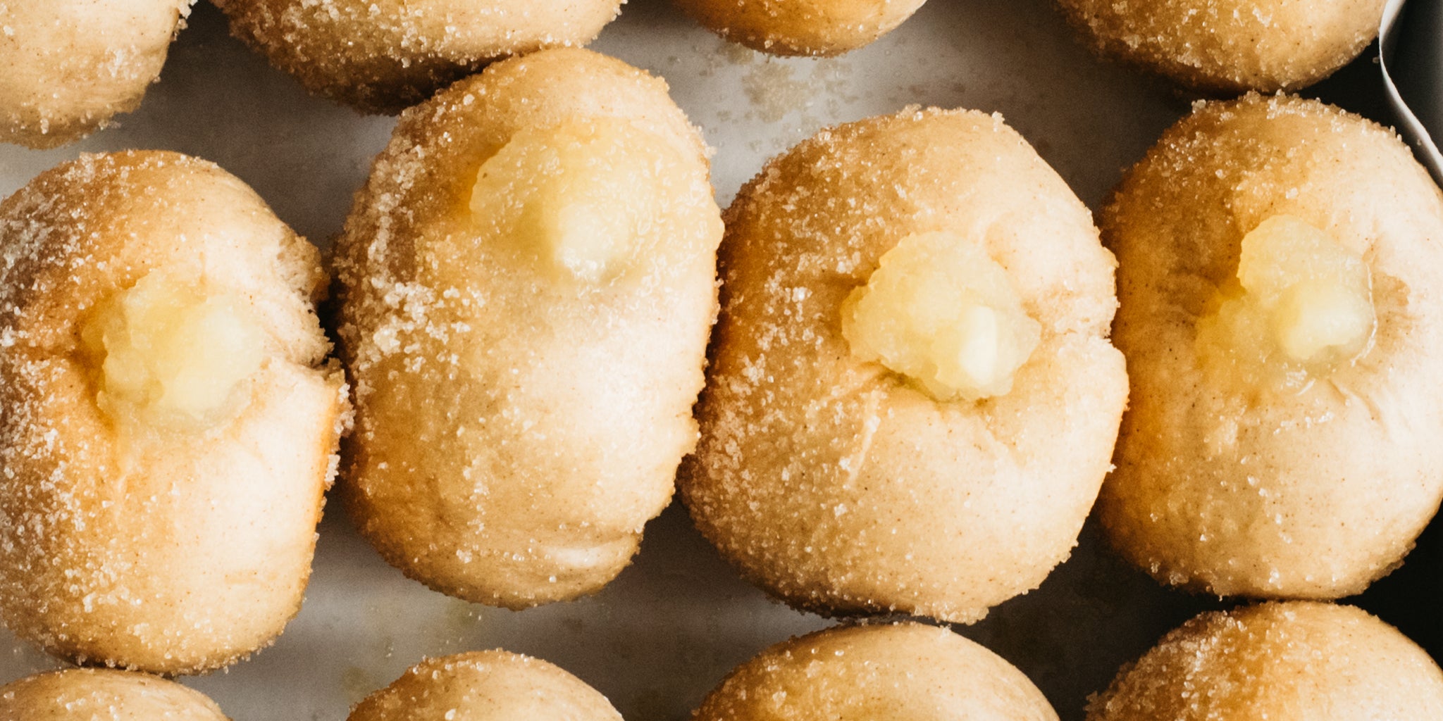 Row of apple doughnuts on baking tray