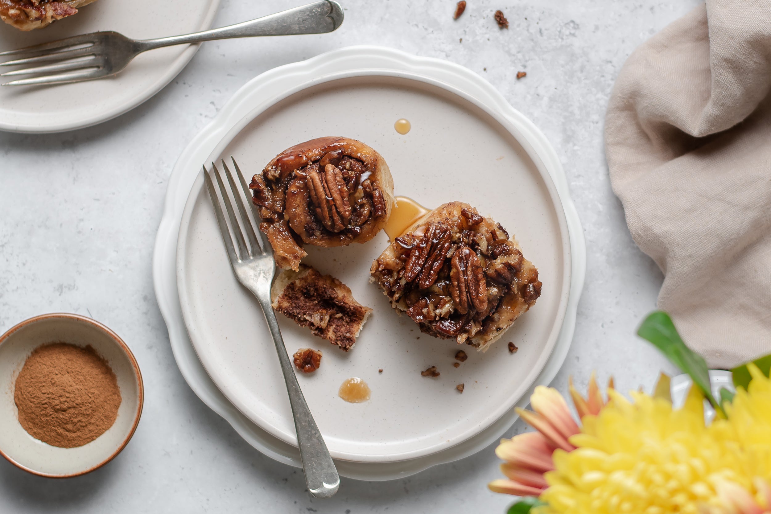 Top view of Low Sugar Sticky Pecan Buns served on a plate with a fork taking a serving out of a sticky bun
