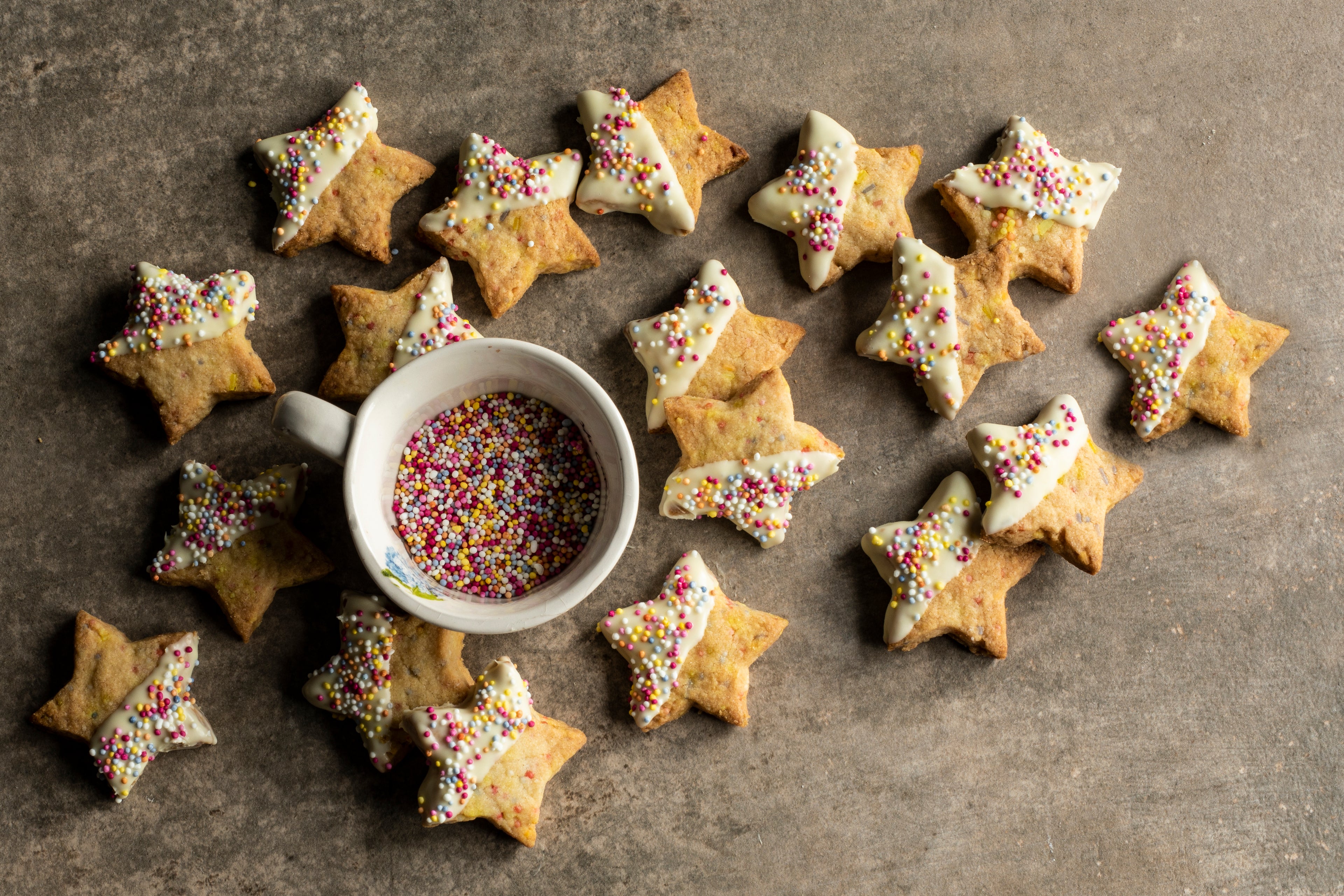 Star biscuits scattered around a small pot of sprinkles