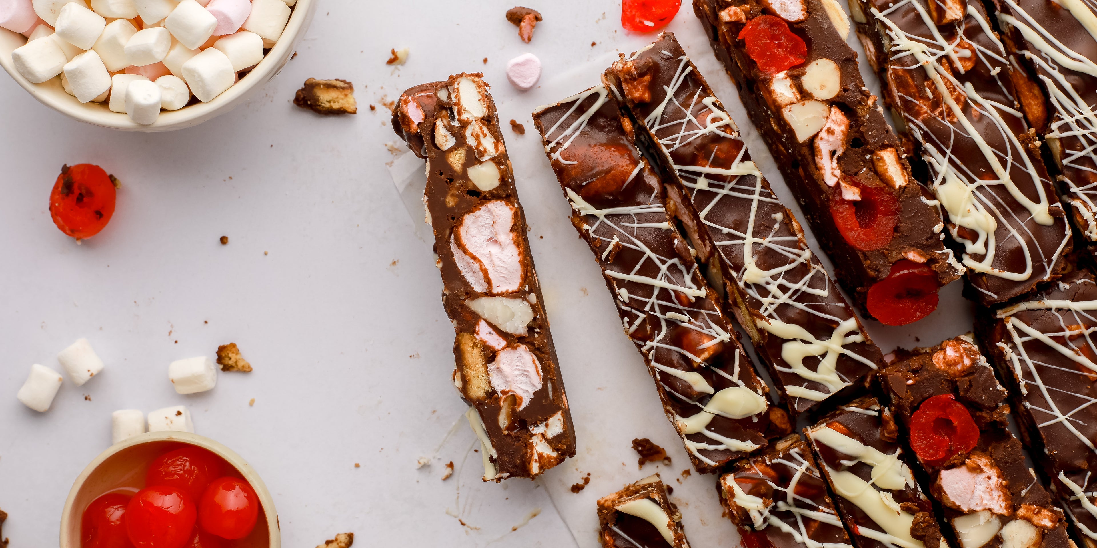 Slices of rocky road beside marshmallows and cherries