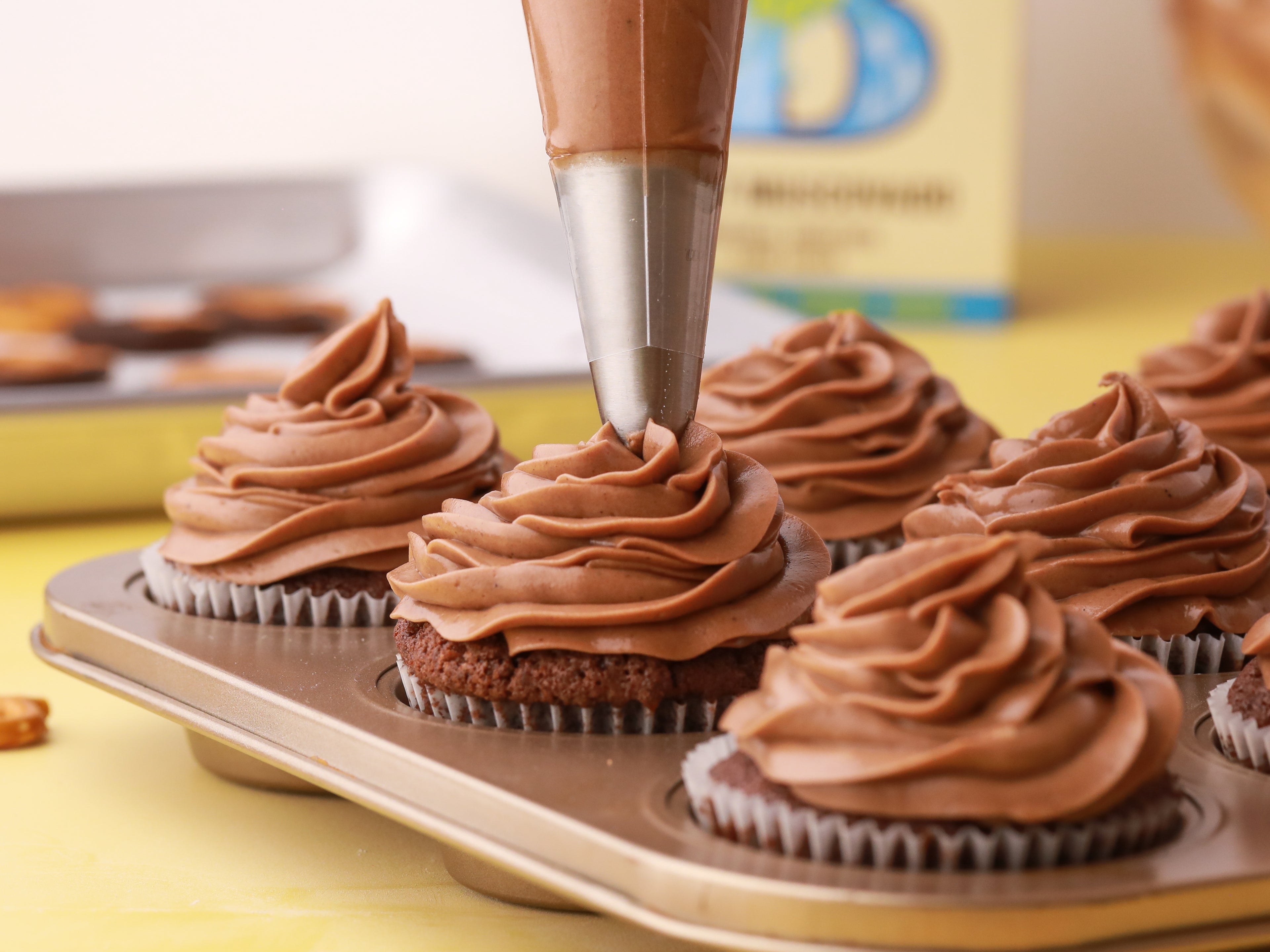 Chocolate buttercream being piped onto cupcake