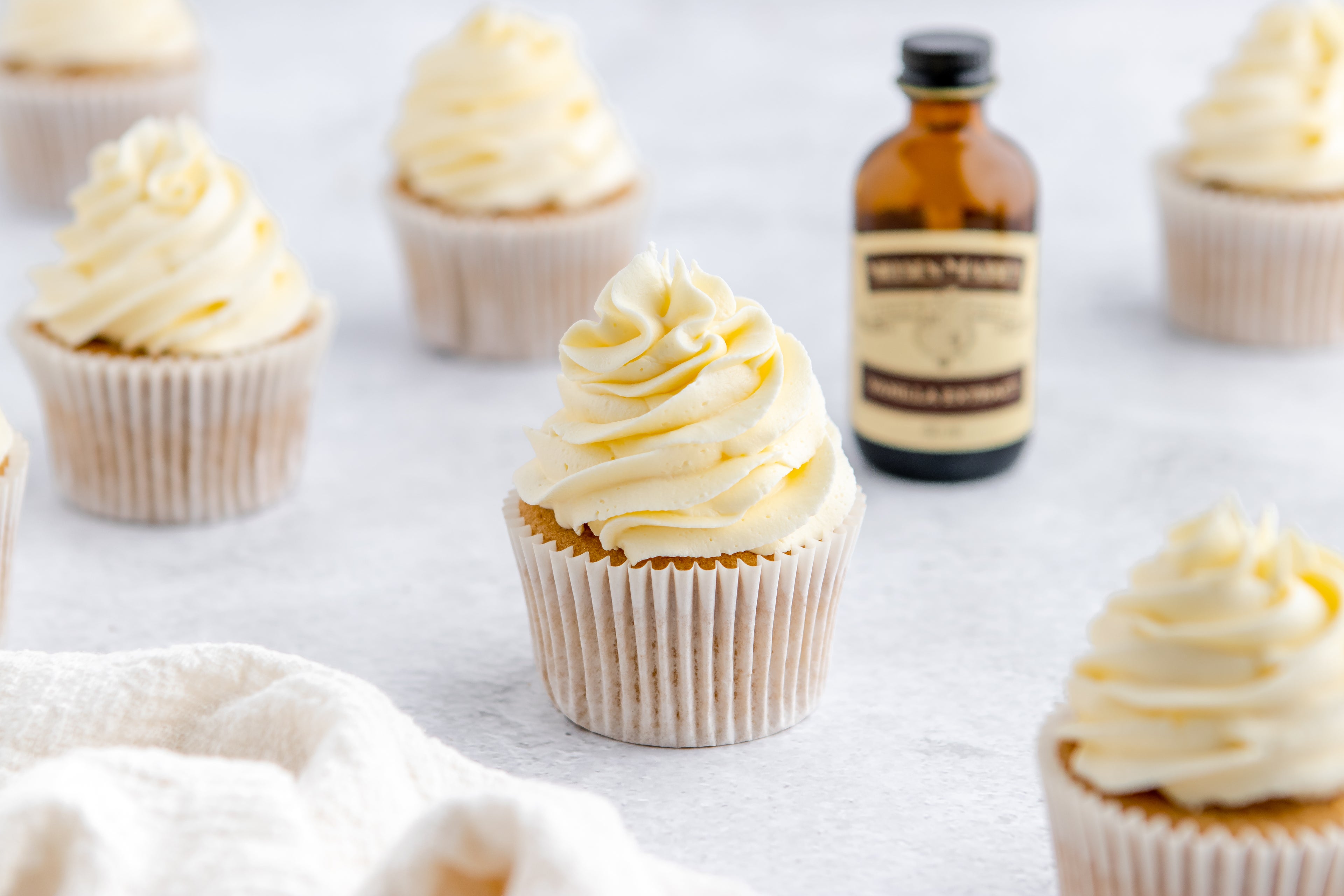 Close up of a Gluten Free Cupcake with a bottle of Neilsen-Massey vanilla extract in the background
