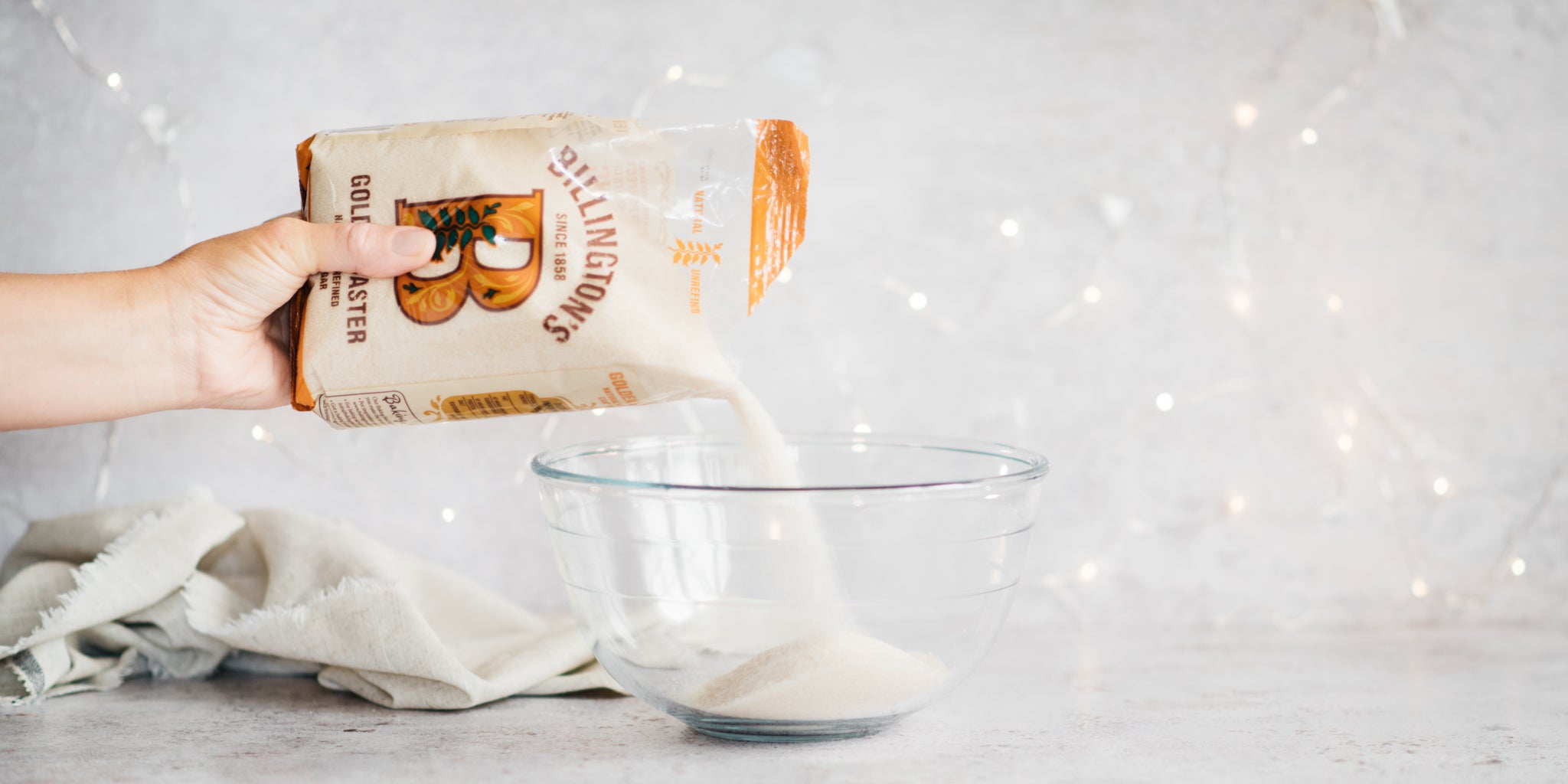 Golden caster sugar being poured into a glass bowl