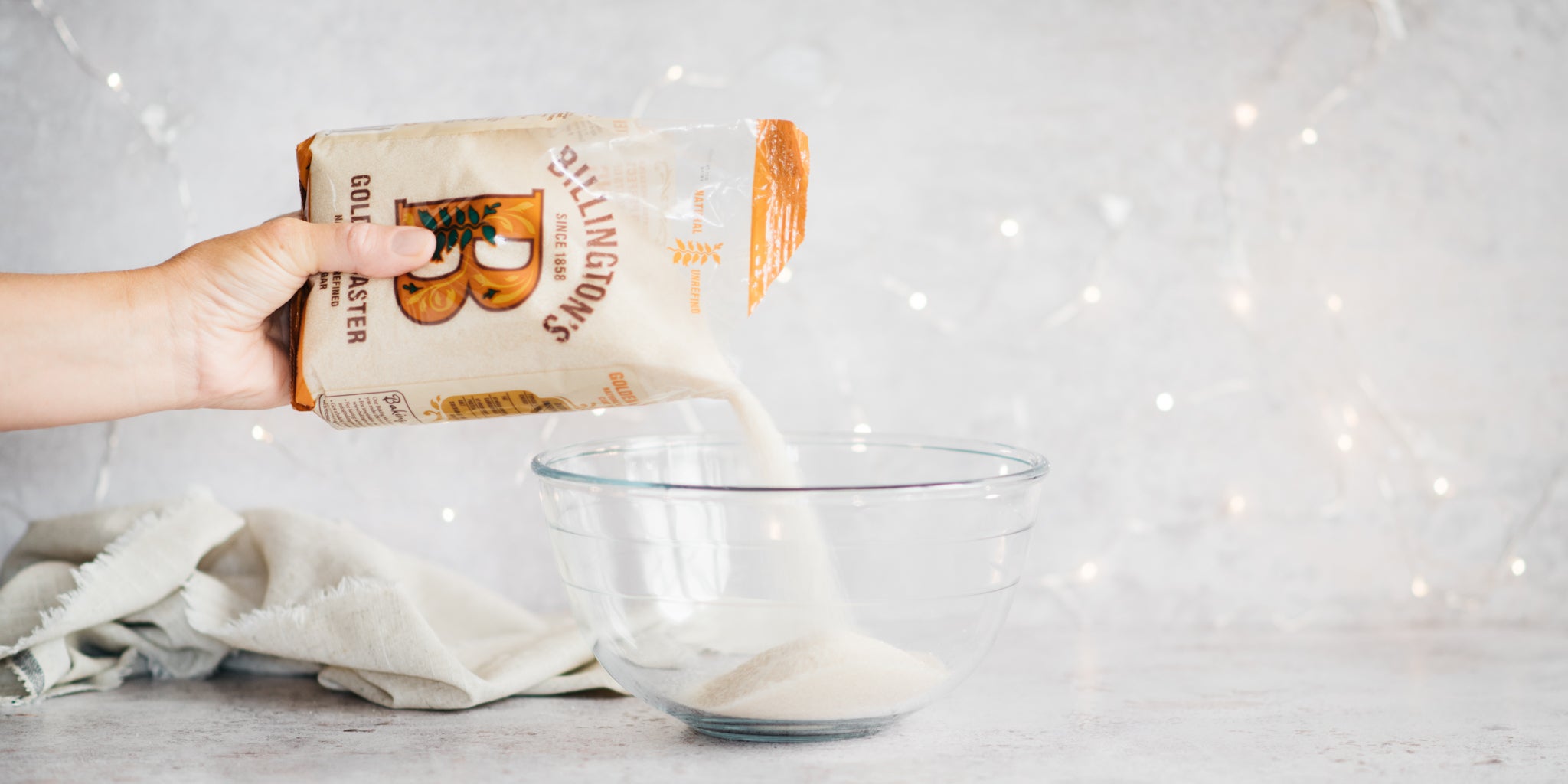 Golden caster sugar  being poured into a glass bowl