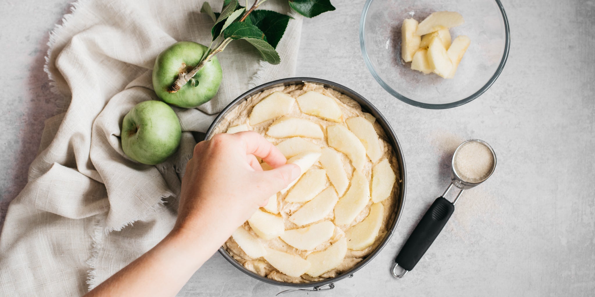 Slices of apple being placed on top of cake mixture