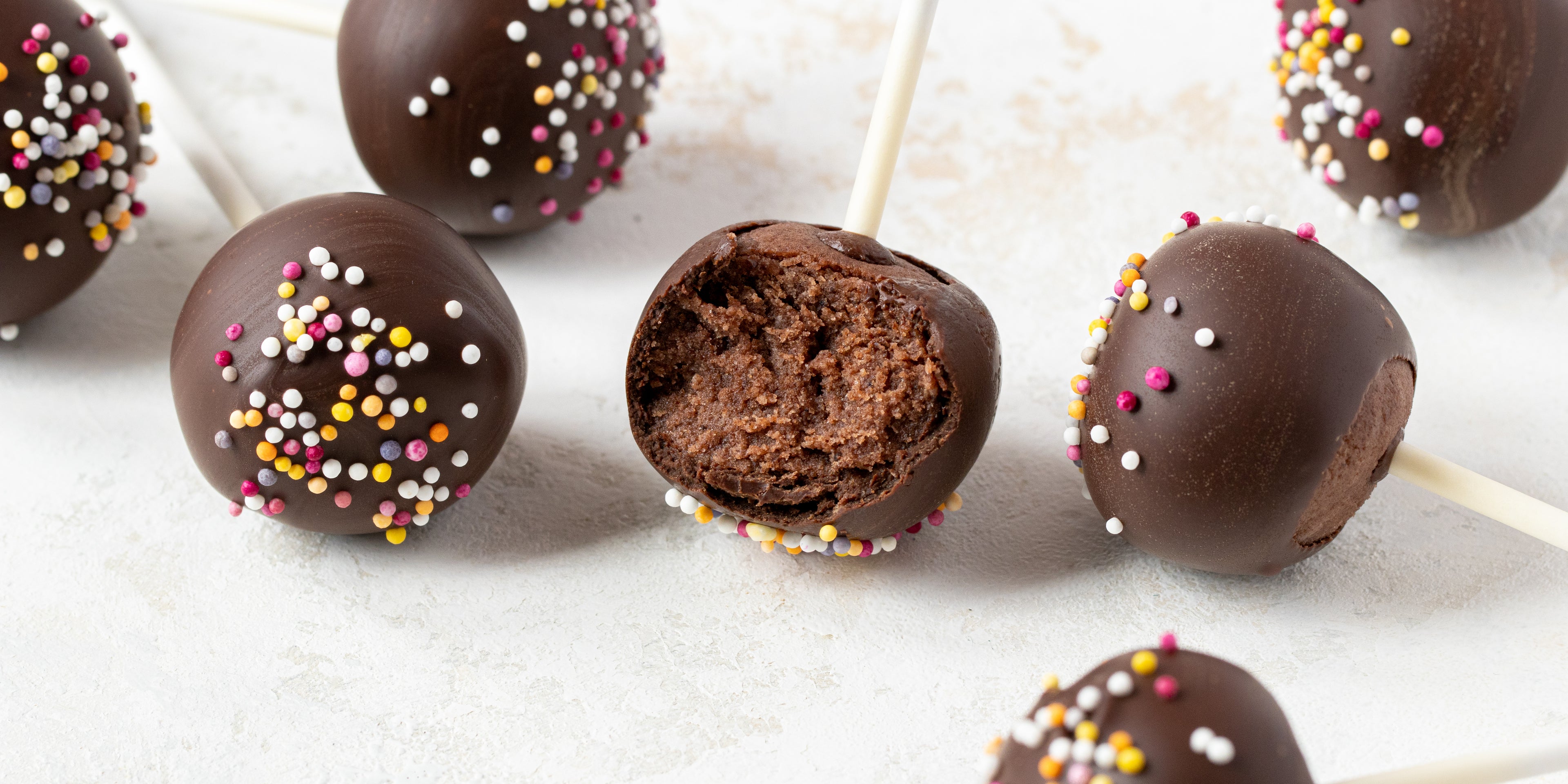 Close up of Chocolate Cake Pops with a bite taken out. Coated in chocolate and sprinkles