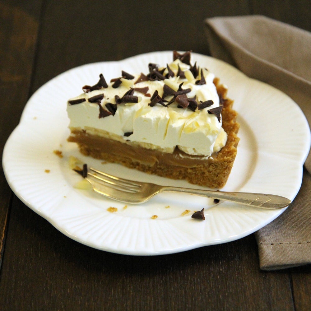 Slice of homemade Banoffee Pie topped with freshly-whipped cream and chocolate