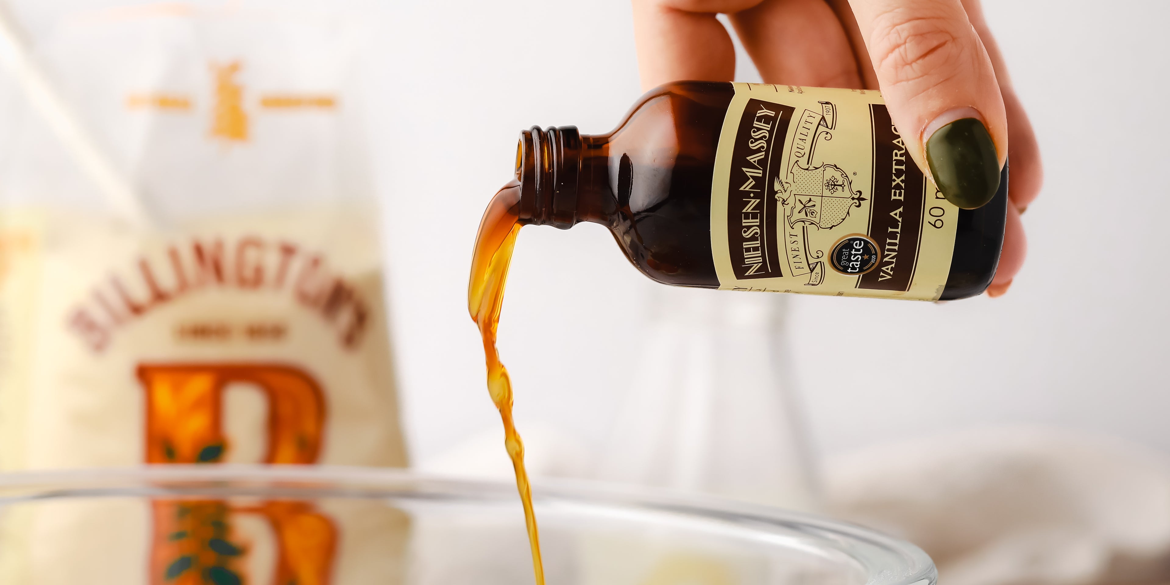 Hand pouring vanilla extract into a bowl