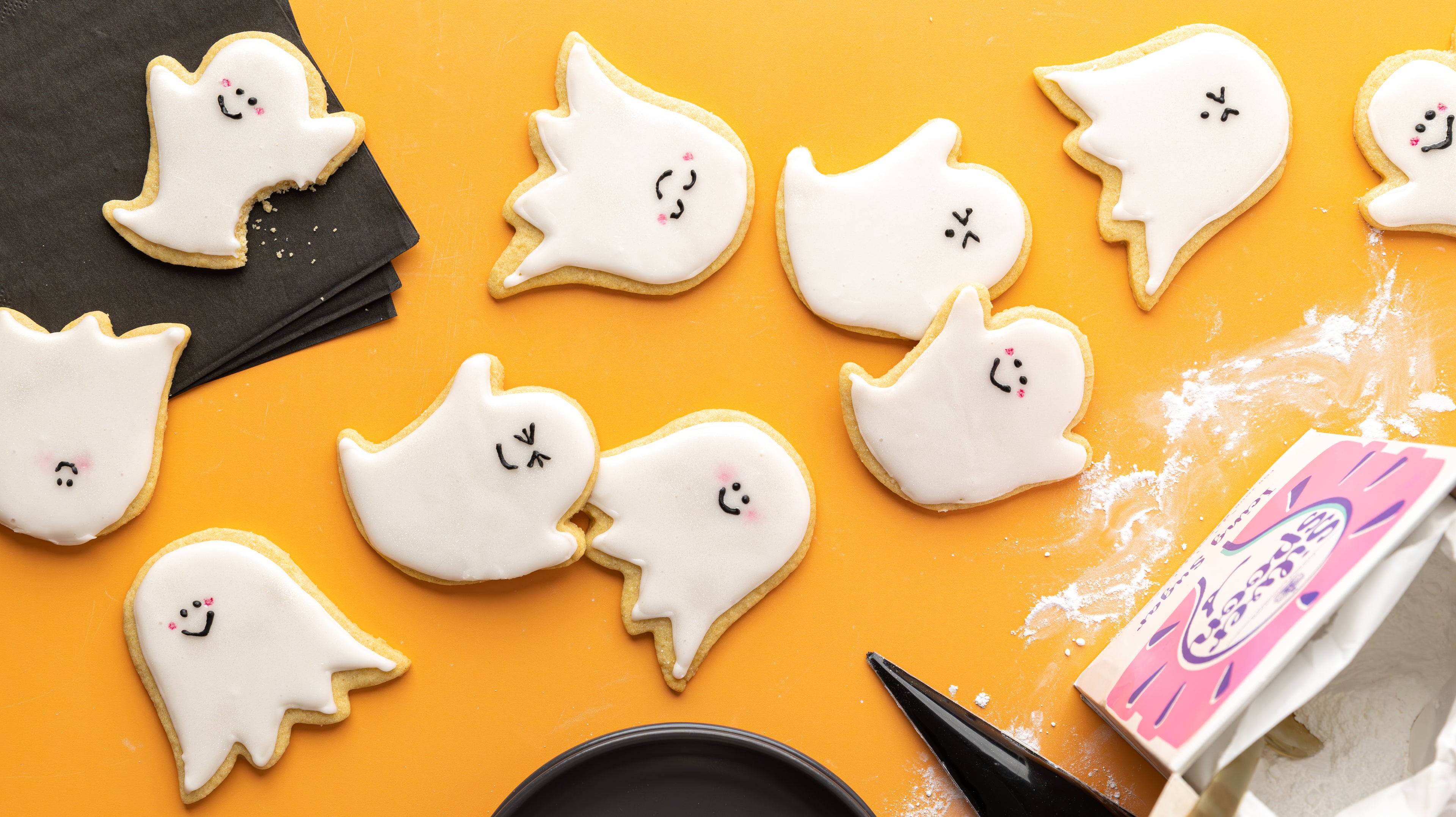 Ghost themed biscuits on an orange background with icing sugar pack